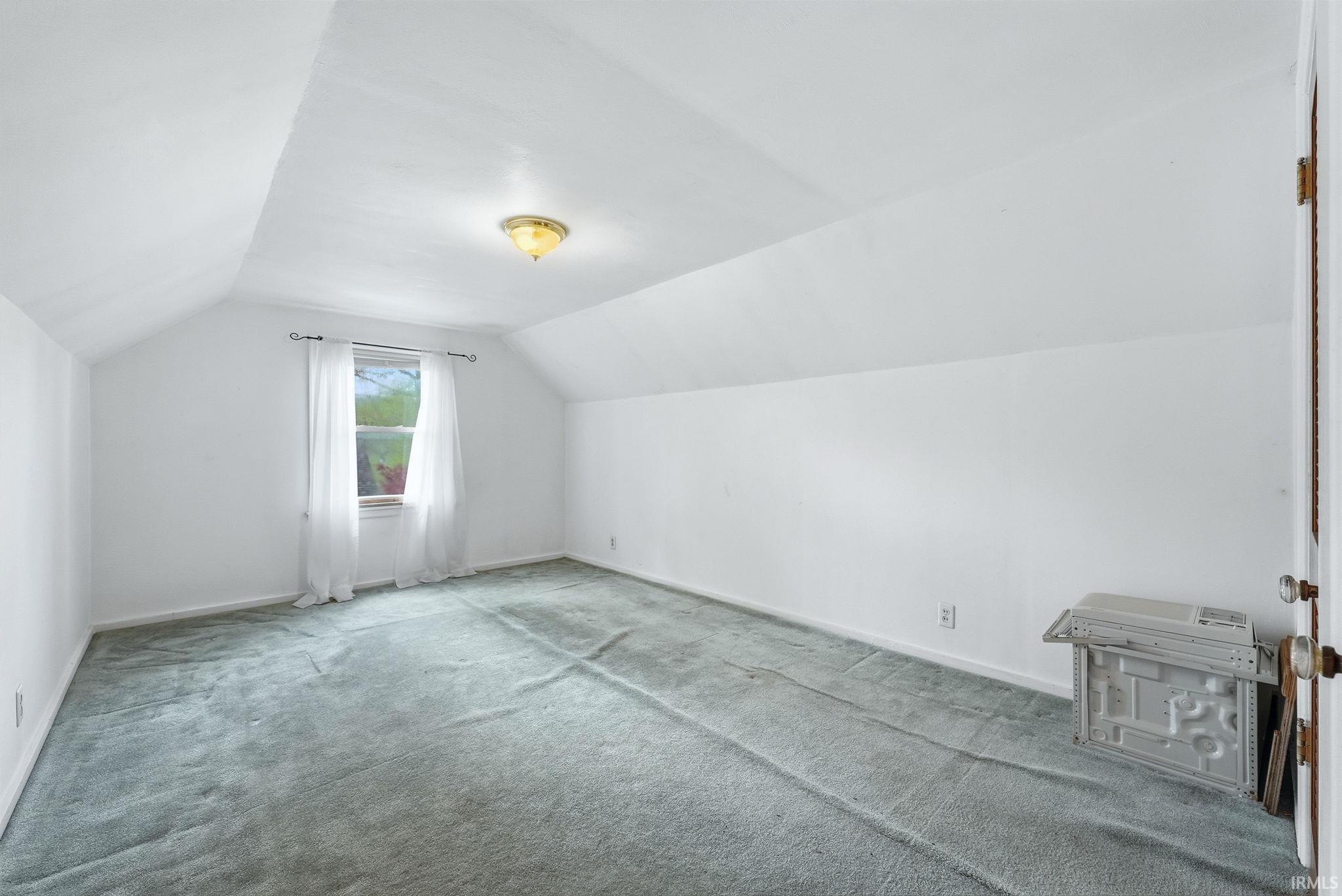 Carpeted room with sloped ceilings and a single window