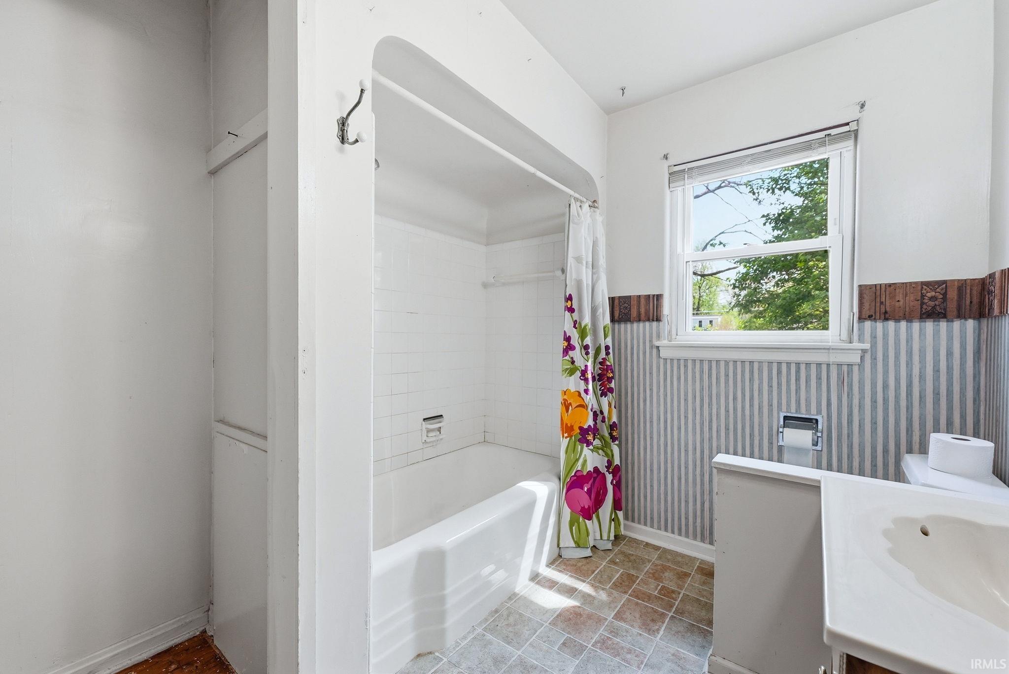 Bathroom featuring a built-in bathtub with white subway tile surround, a single window, and a vanity with an integrated sink