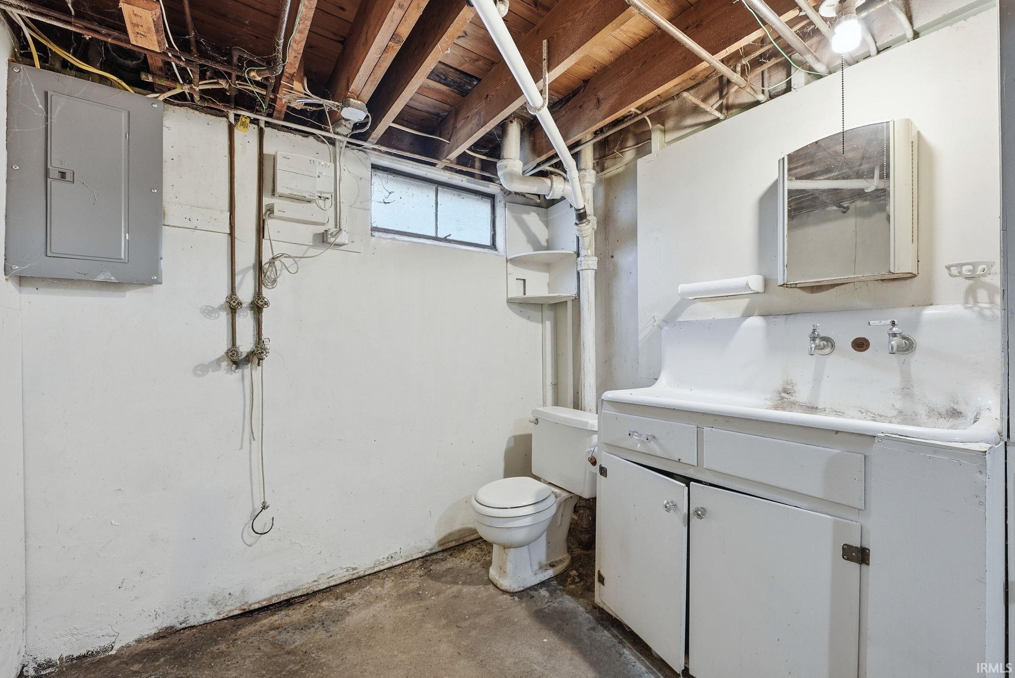 Basement utility area featuring exposed wood joists and an electrical panel