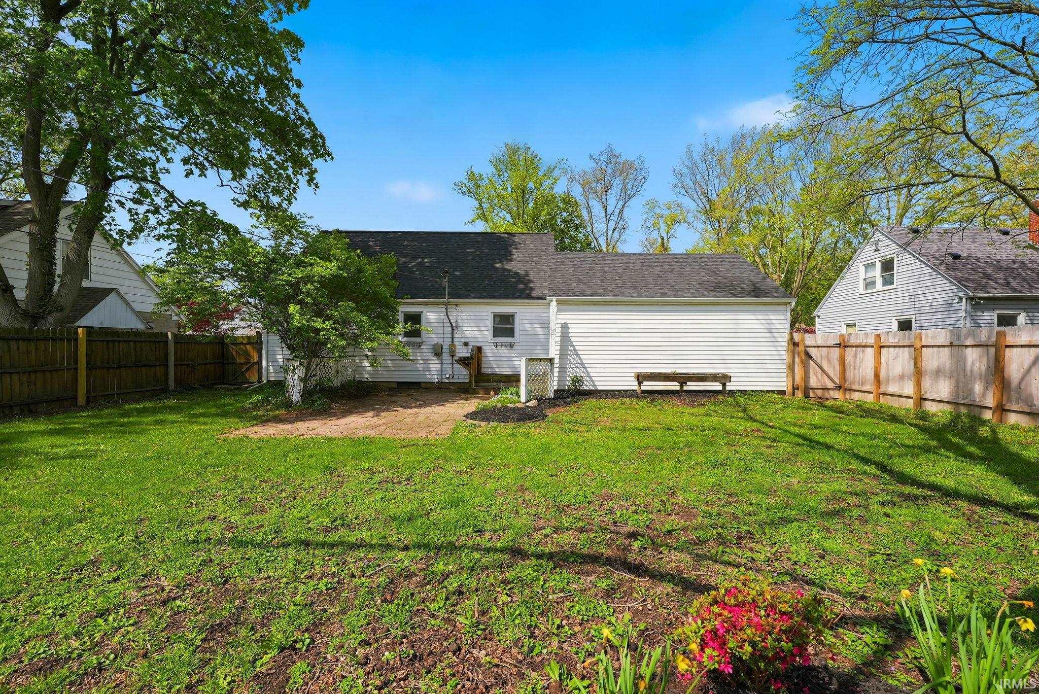 Expansive backyard featuring a green lawn, mature trees, and a private wood fence