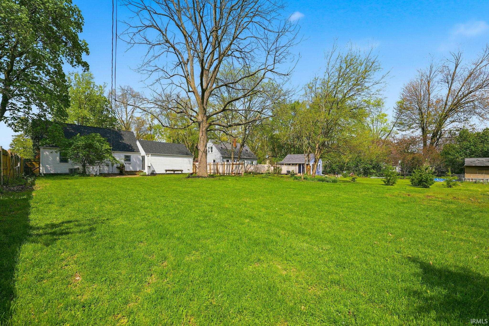 Expansive green lawn with mature trees providing natural shade