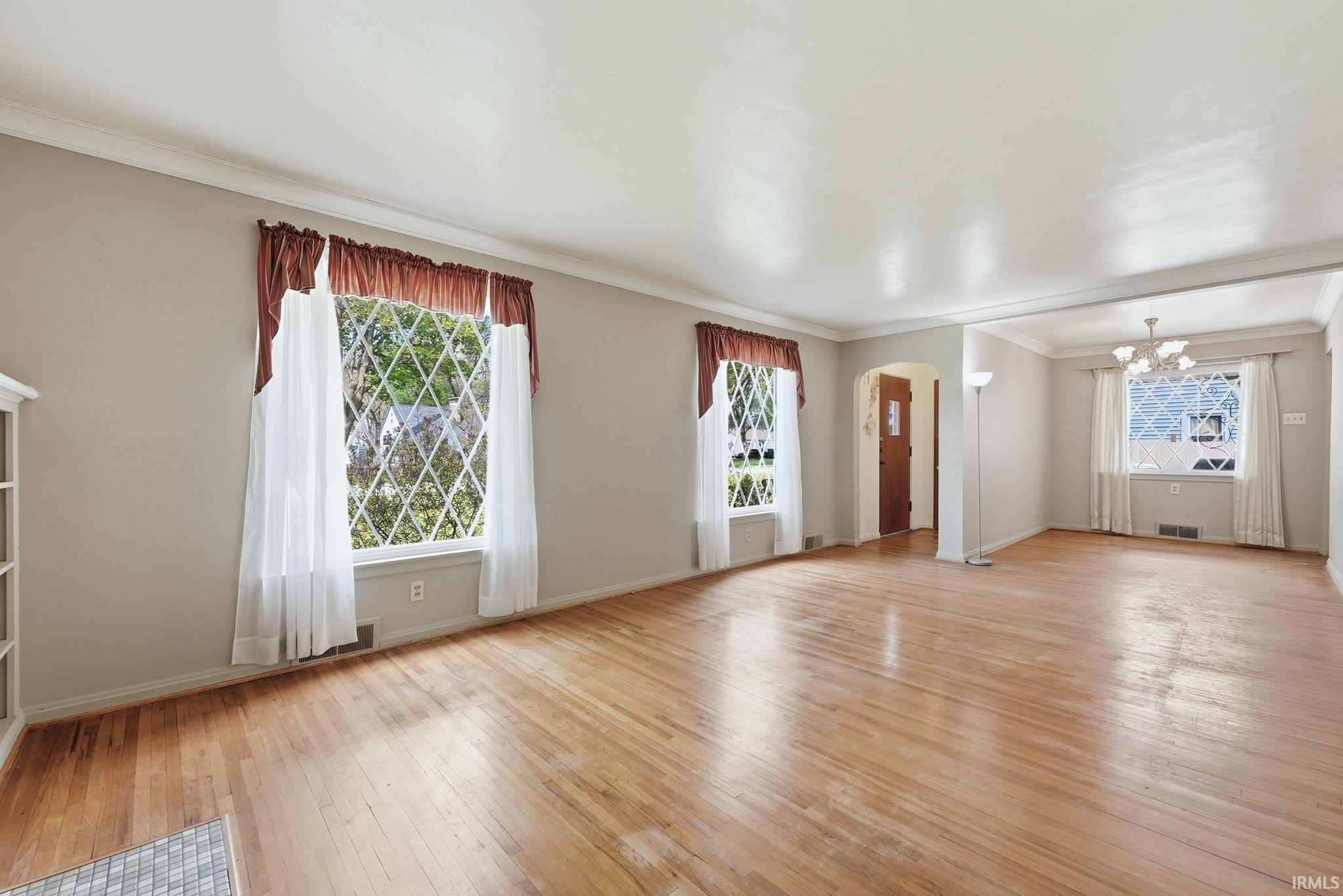 Expansive living space featuring wood-finish flooring, diamond-pane windows, and a coved ceiling