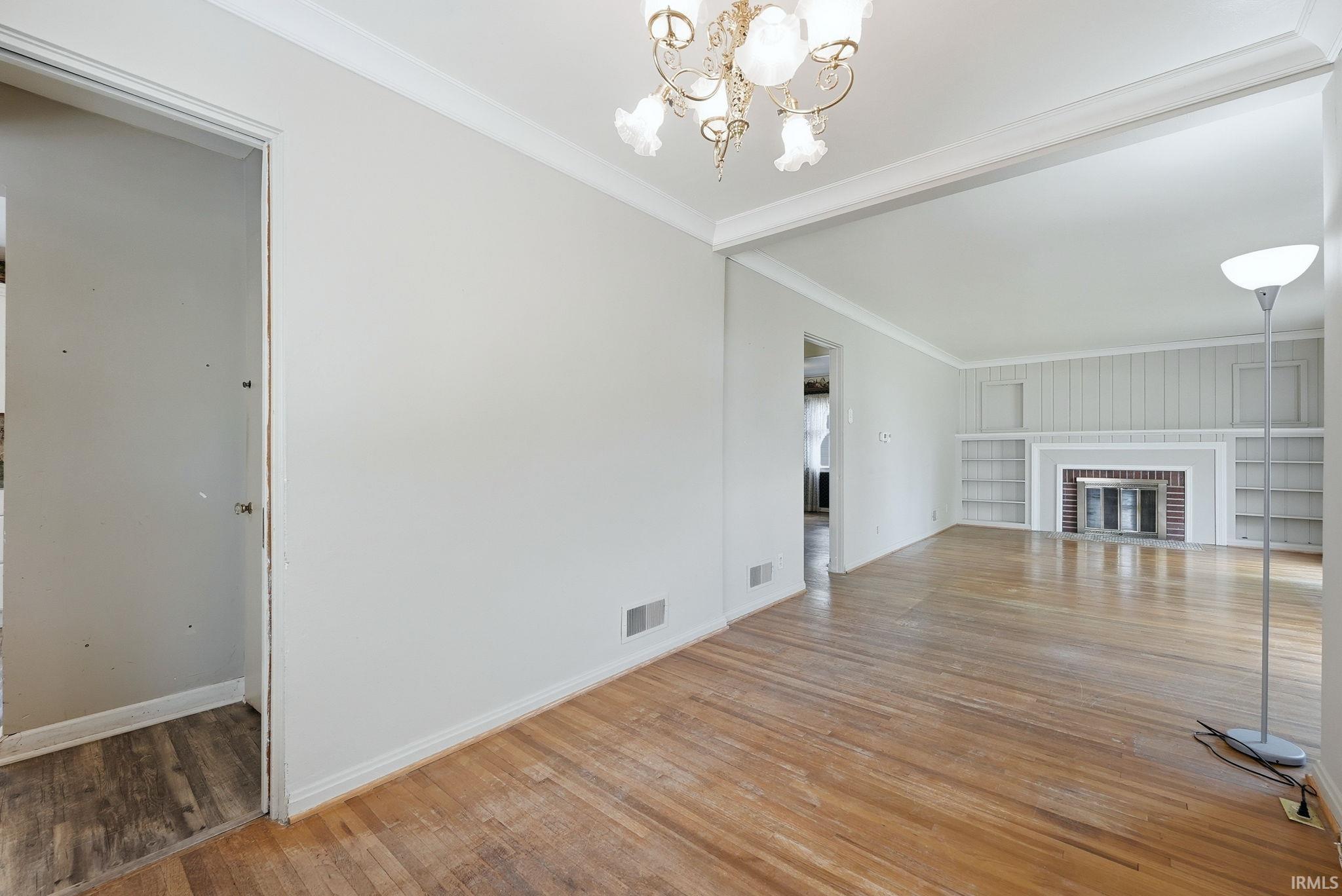 Hardwood flooring throughout a spacious room featuring a decorative chandelier
