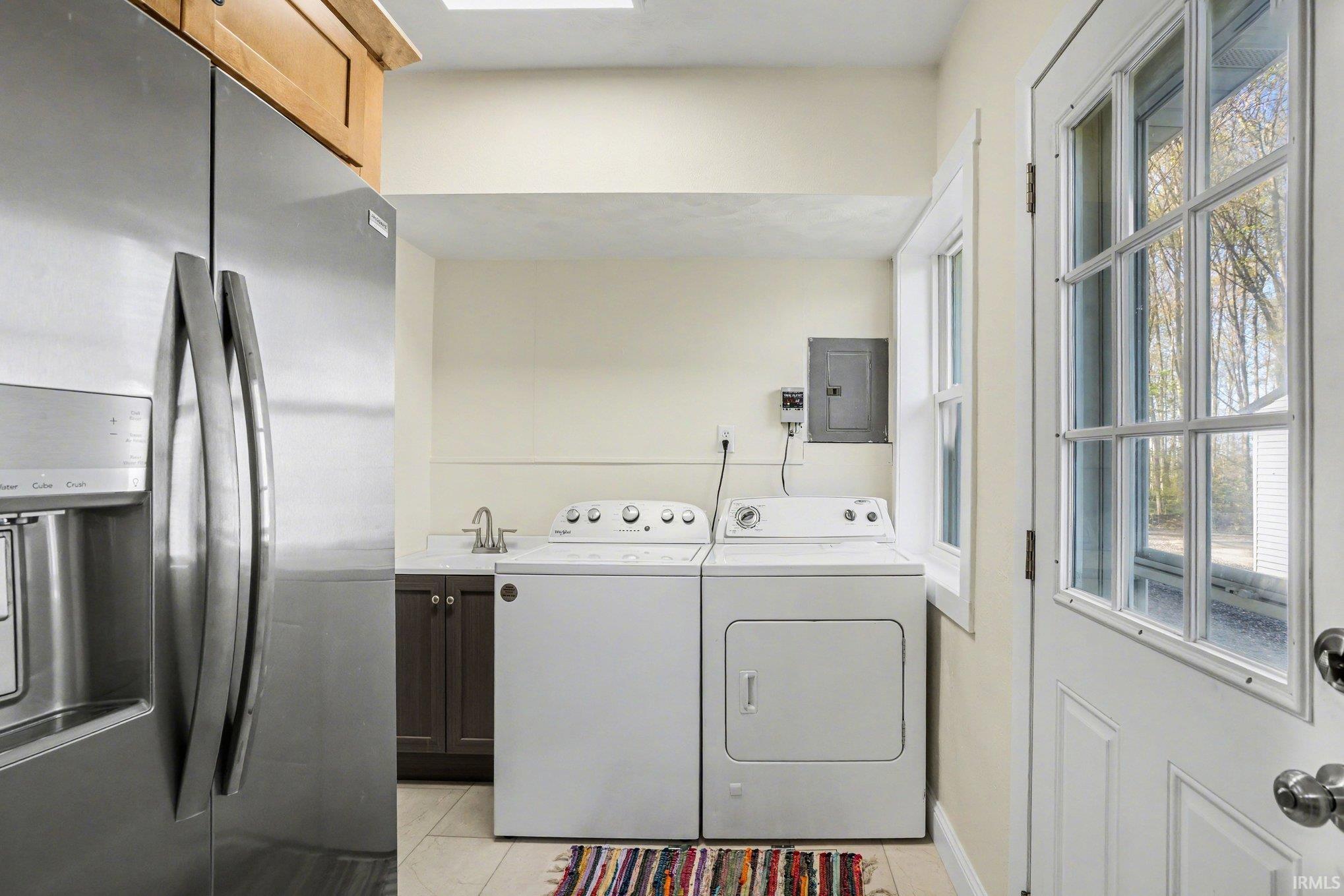 Utility area featuring a built-in sink with cabinetry, white appliance set, and light-toned tile flooring