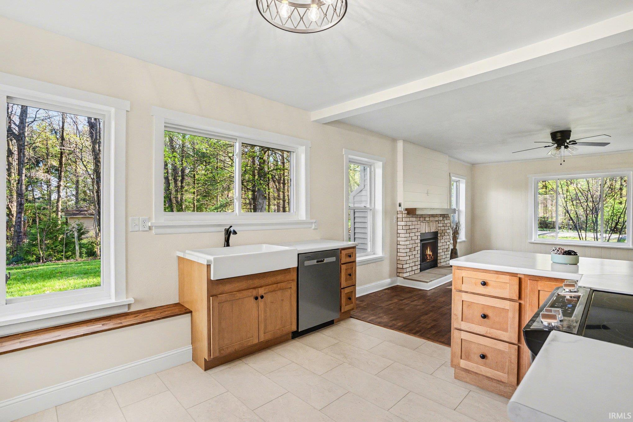 Open-concept kitchen featuring light wood cabinetry, a farmhouse sink, and a dishwasher