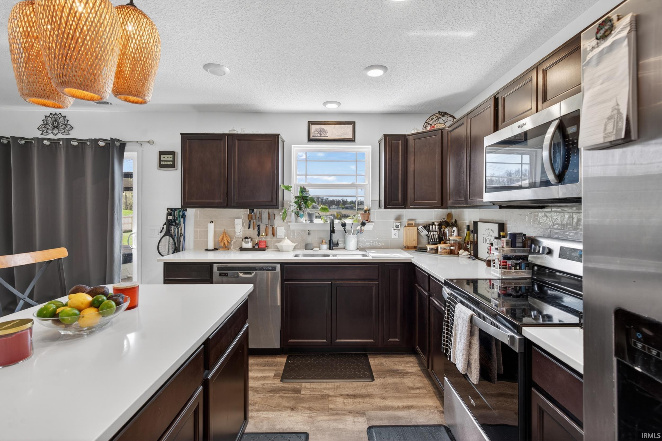Kitchen featuring wood-finish flooring, dark wood cabinetry, and white countertops
