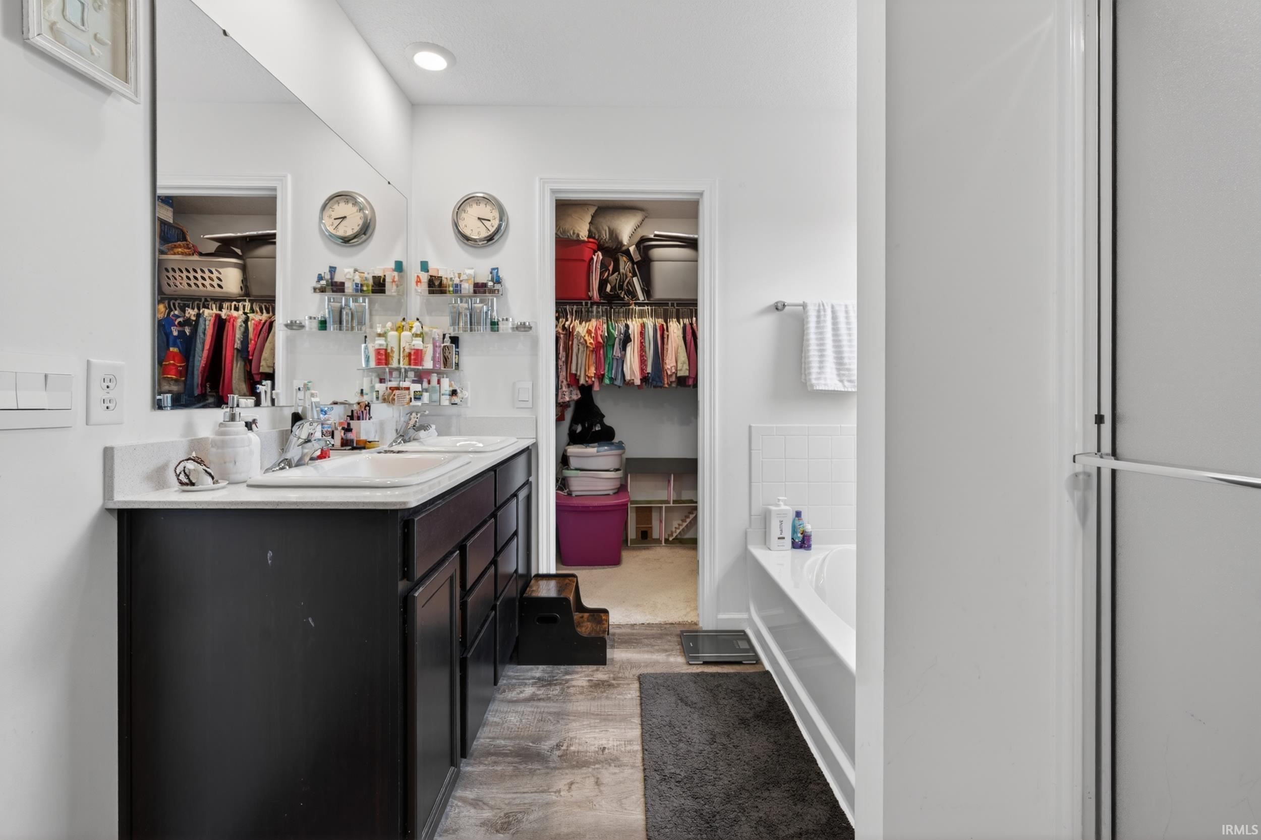 Bathroom vanity featuring dual under-mount sinks, a light-colored countertop, and dark cabinetry with storage
