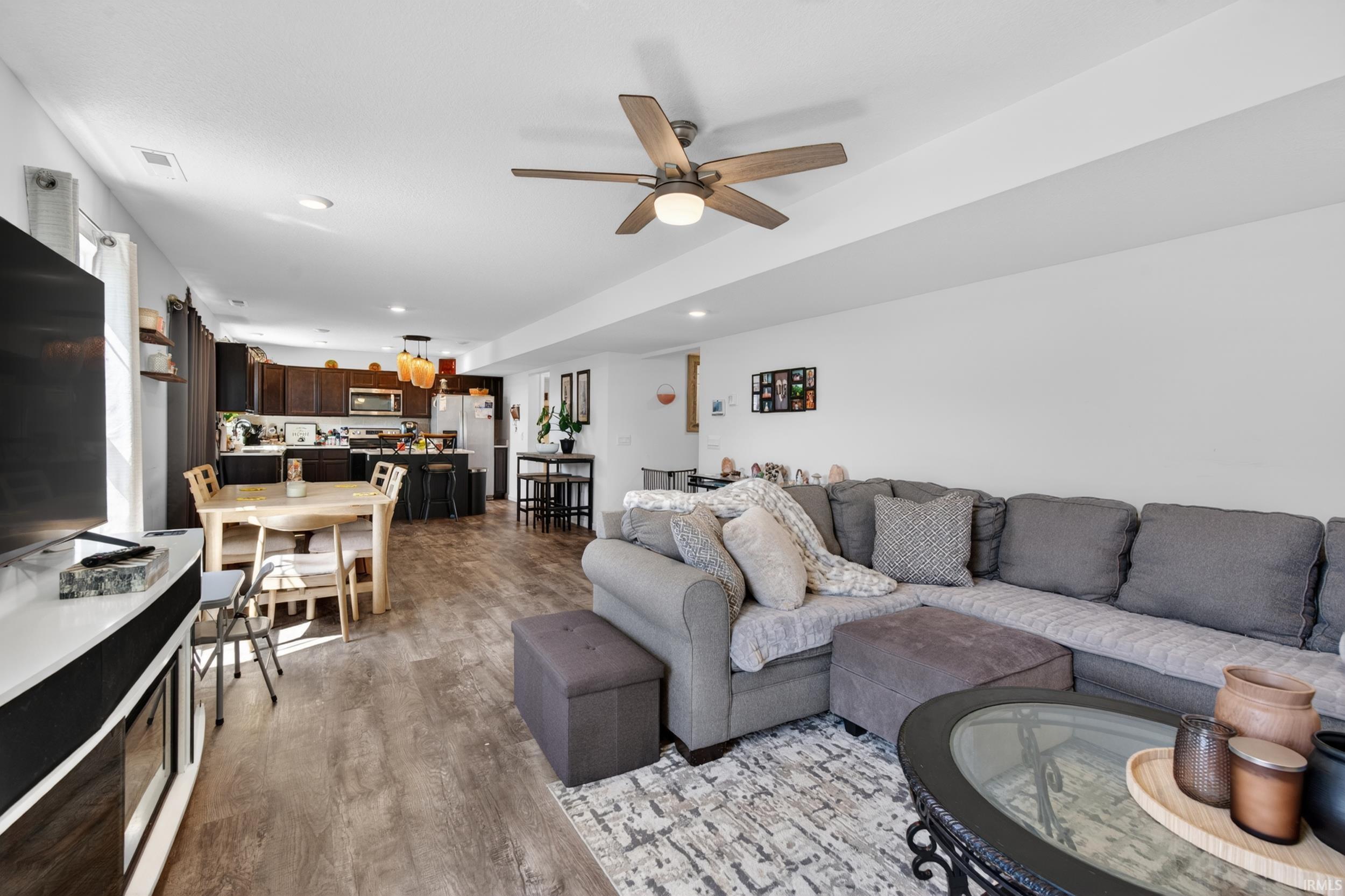 Open-concept living space featuring wood-finish flooring, recessed lighting, and a ceiling fan