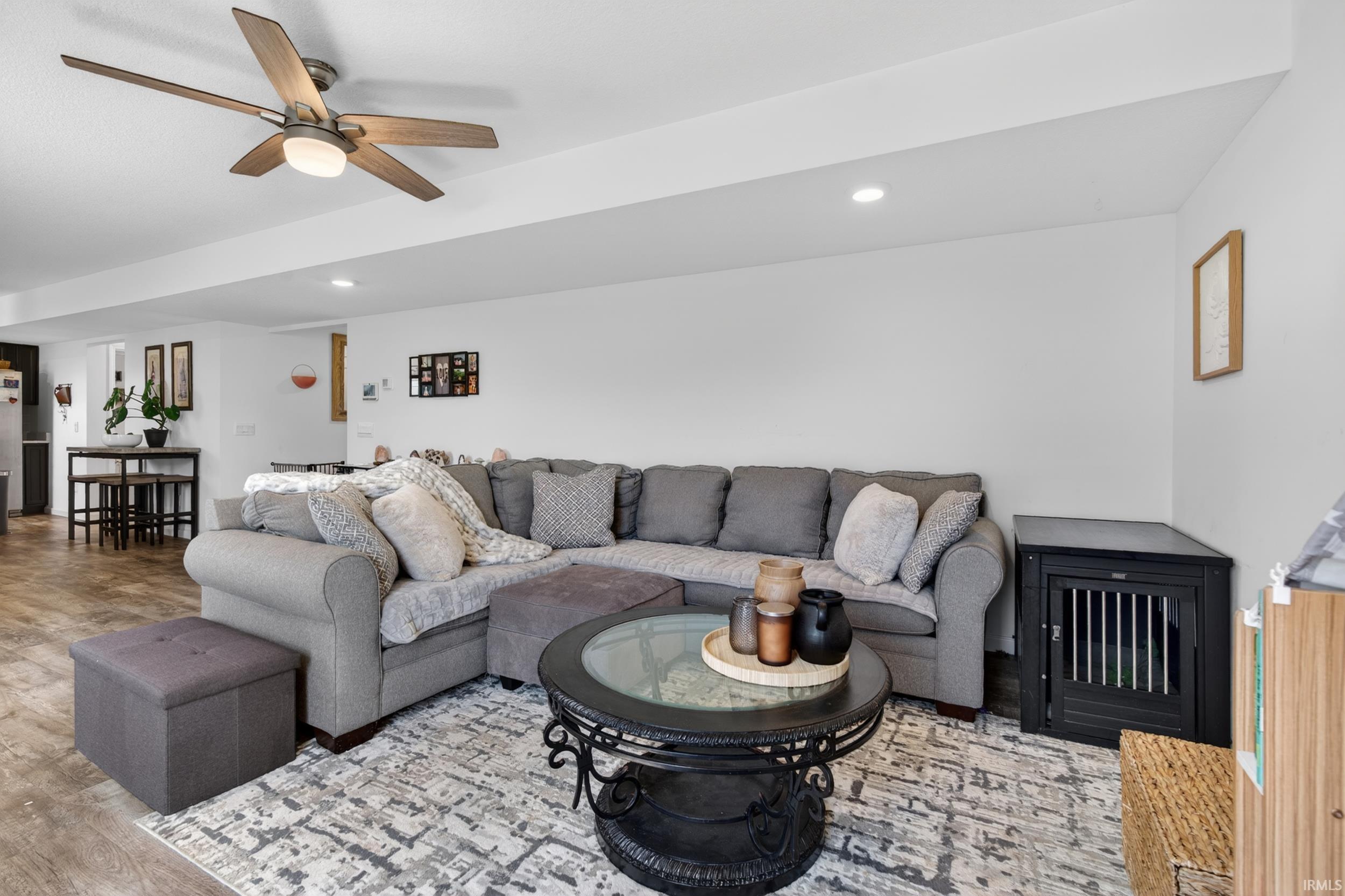 Open-concept living area featuring a ceiling fan with integrated lighting, recessed lighting, wood-finish flooring, and crisp white walls