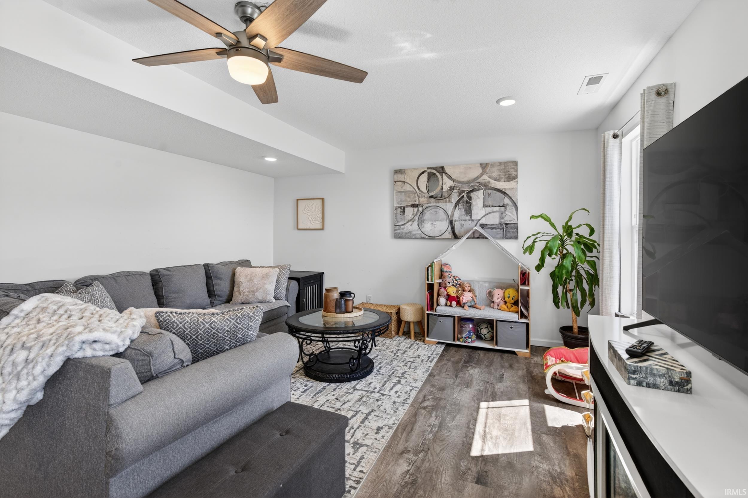 Spacious living area featuring wood-finish flooring, recessed lighting, and a ceiling fan