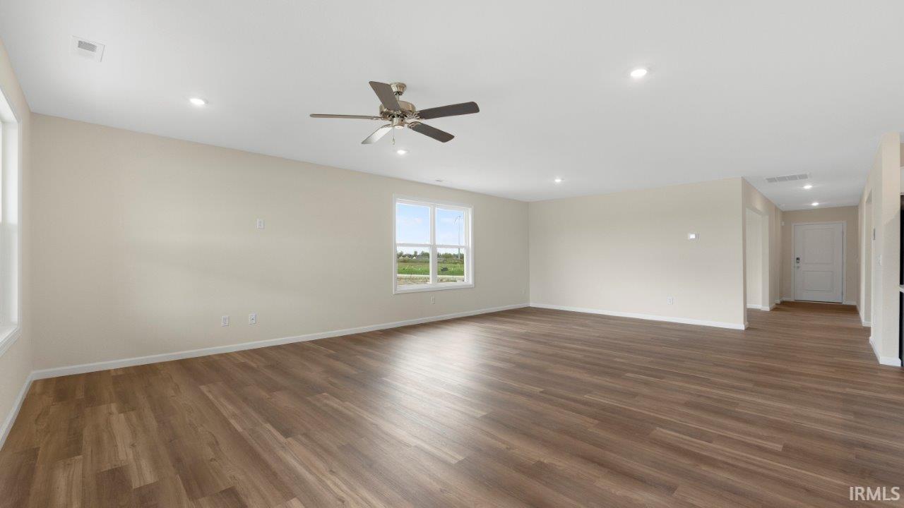 Spacious room featuring wood-finish flooring, light neutral wall paint, recessed lighting, and a ceiling fan