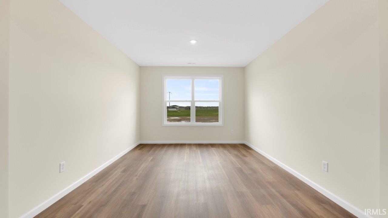 Bright room featuring a single window, recessed lighting, wood-finish flooring, and crisp white baseboards