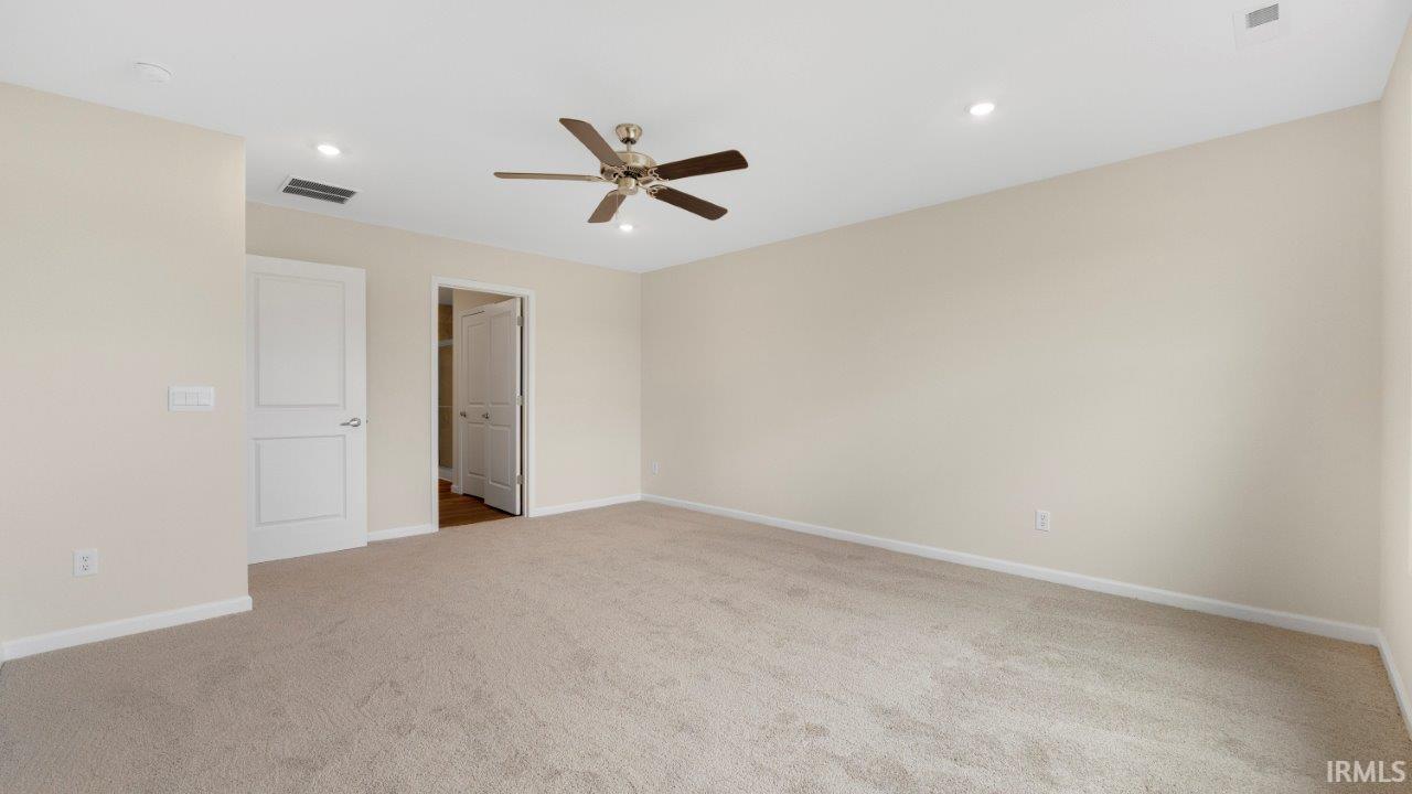 Expansive carpeted room featuring a ceiling fan with integrated lighting, recessed ceiling lights, and multiple white paneled doors
