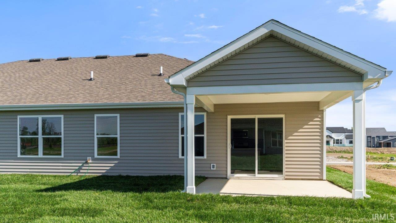 Rear exterior featuring a covered patio with a sliding glass door, white trim, and a concrete pad