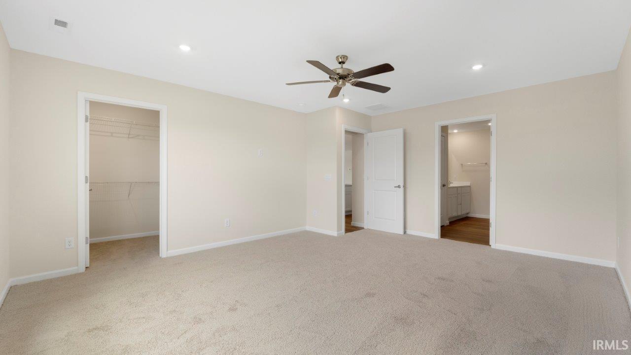 Spacious room featuring neutral carpeting, recessed lighting, and a ceiling fan