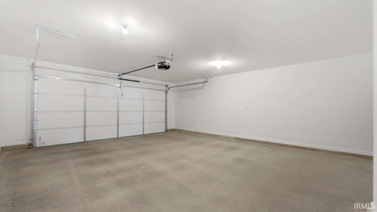 Spacious two-car garage featuring a sectional overhead door, automatic opener, concrete flooring, recessed lighting, and painted walls