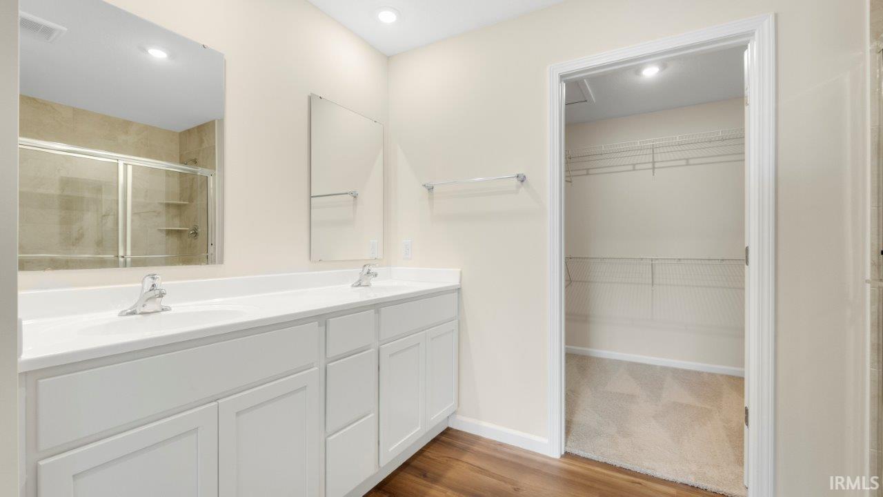 Dual vanity with white cabinetry, polished chrome faucets, and a large wall-mounted mirror