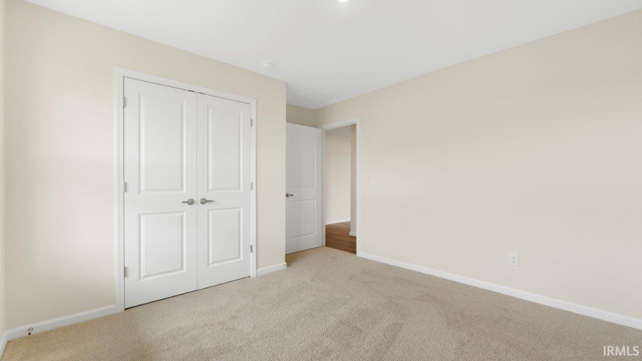 Carpeted room with a double-door closet featuring paneled doors and brushed nickel hardware