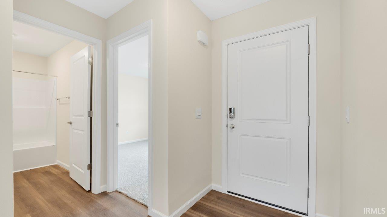 Entryway featuring wood-finish flooring, a white paneled door, and neutral wall paint
