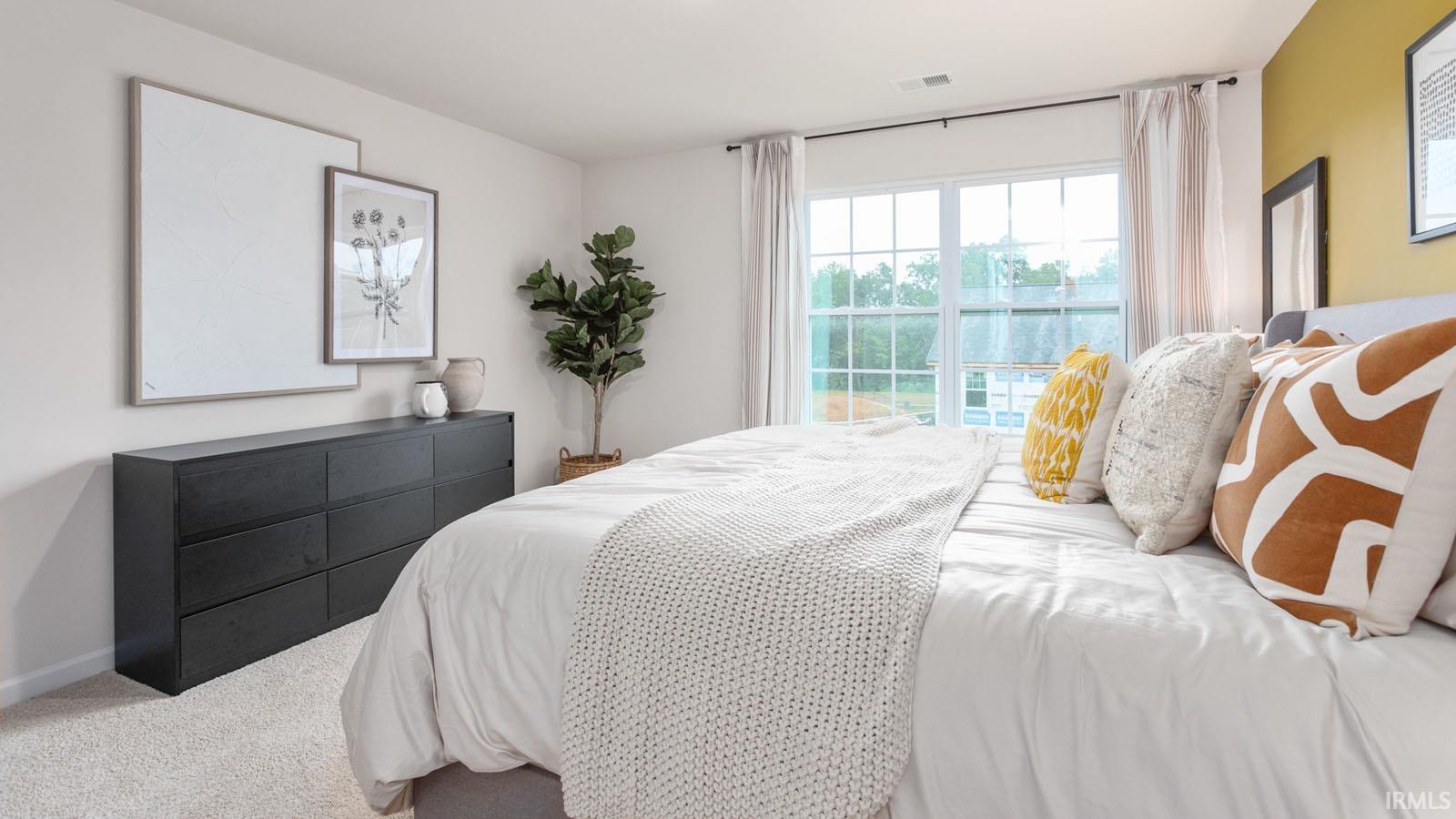 Bright interior space featuring a large window with white framing, soft carpeting, and neutral wall tones