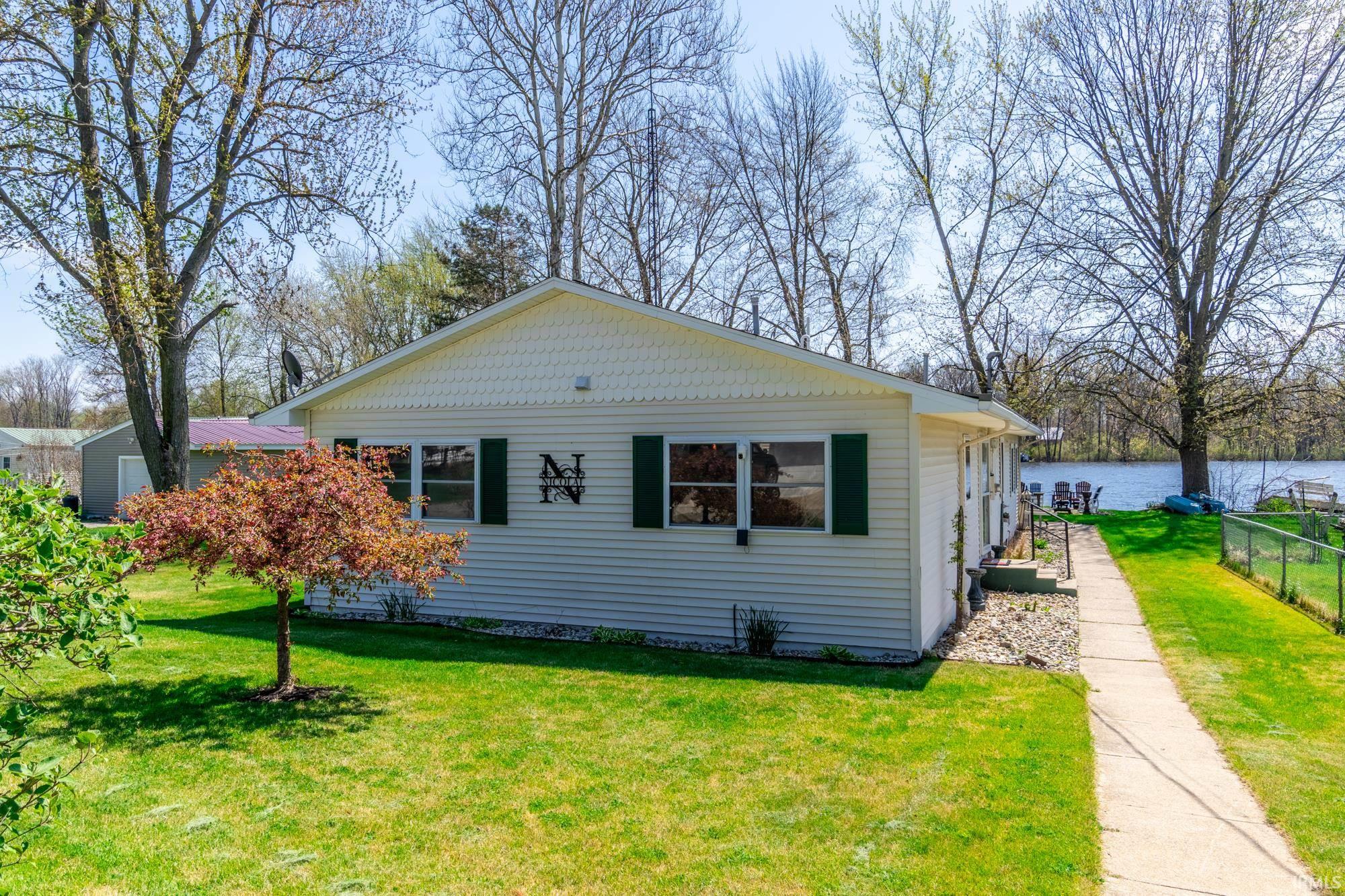 Ranch-style residence featuring light-colored siding, dark green shutters, and a well-maintained lawn