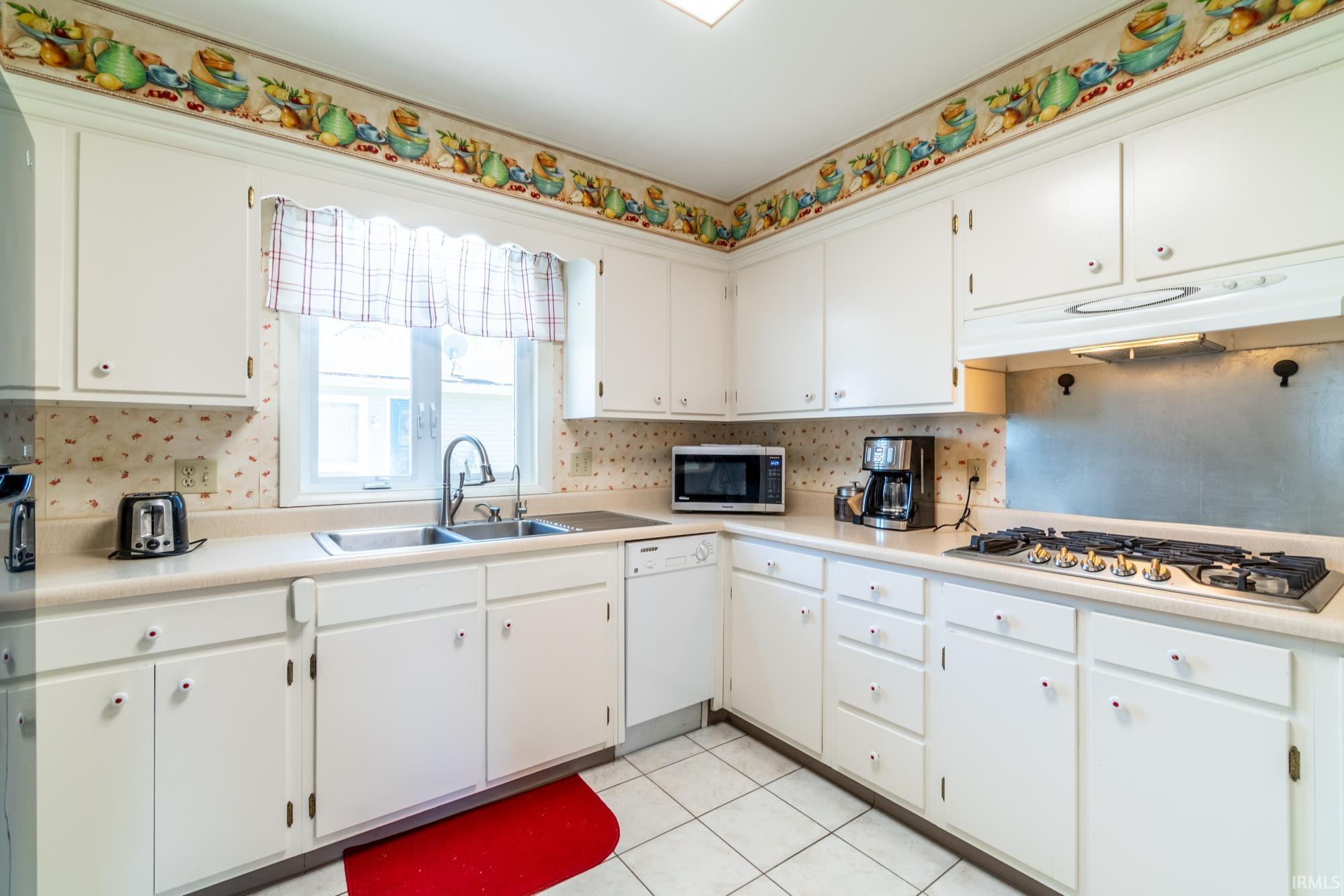 White cabinetry with light countertops, a double basin sink, and a built-in cooktop