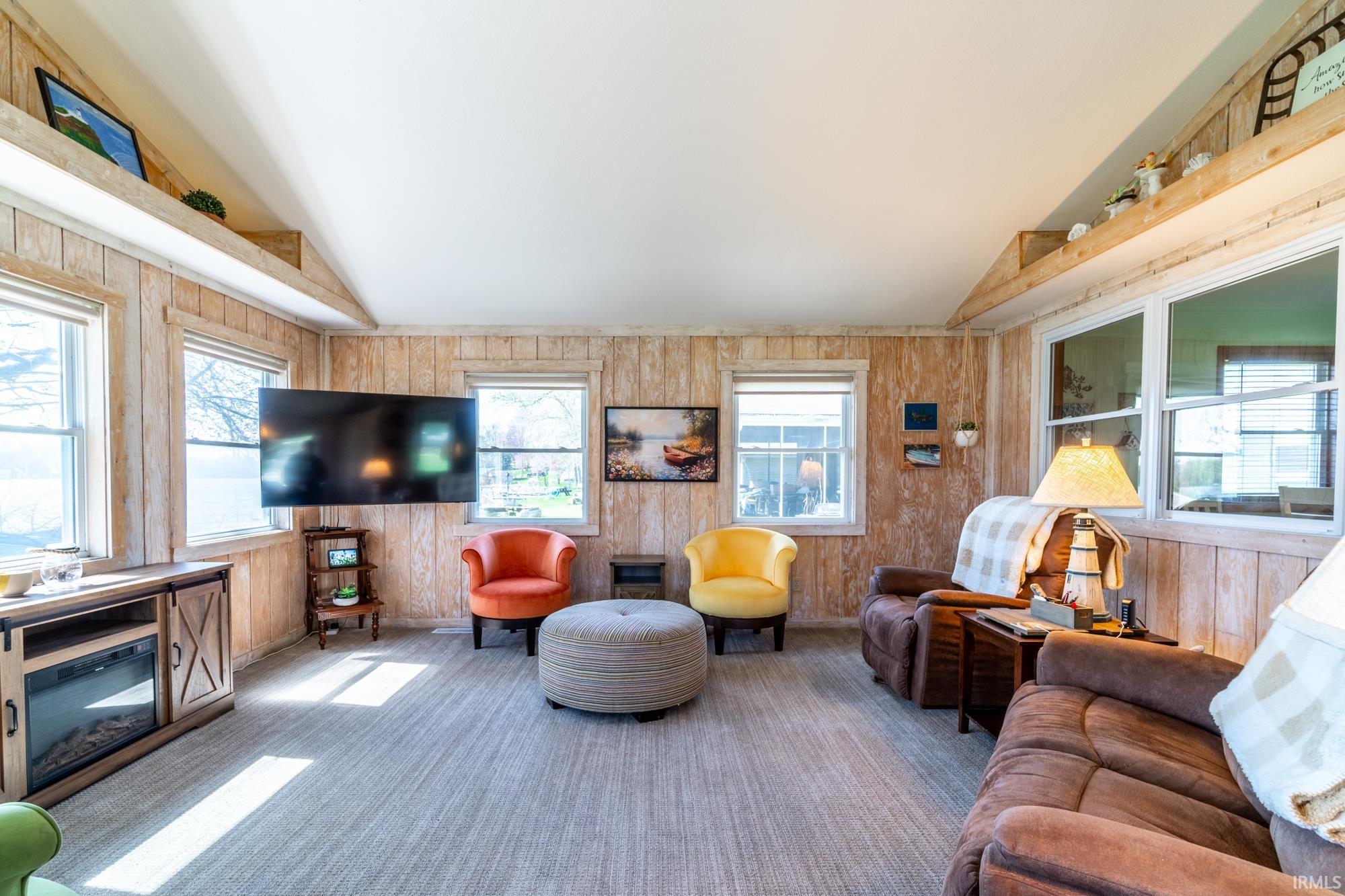 Interior room featuring horizontal wood paneling, multiple windows with white trim, and light-toned flooring