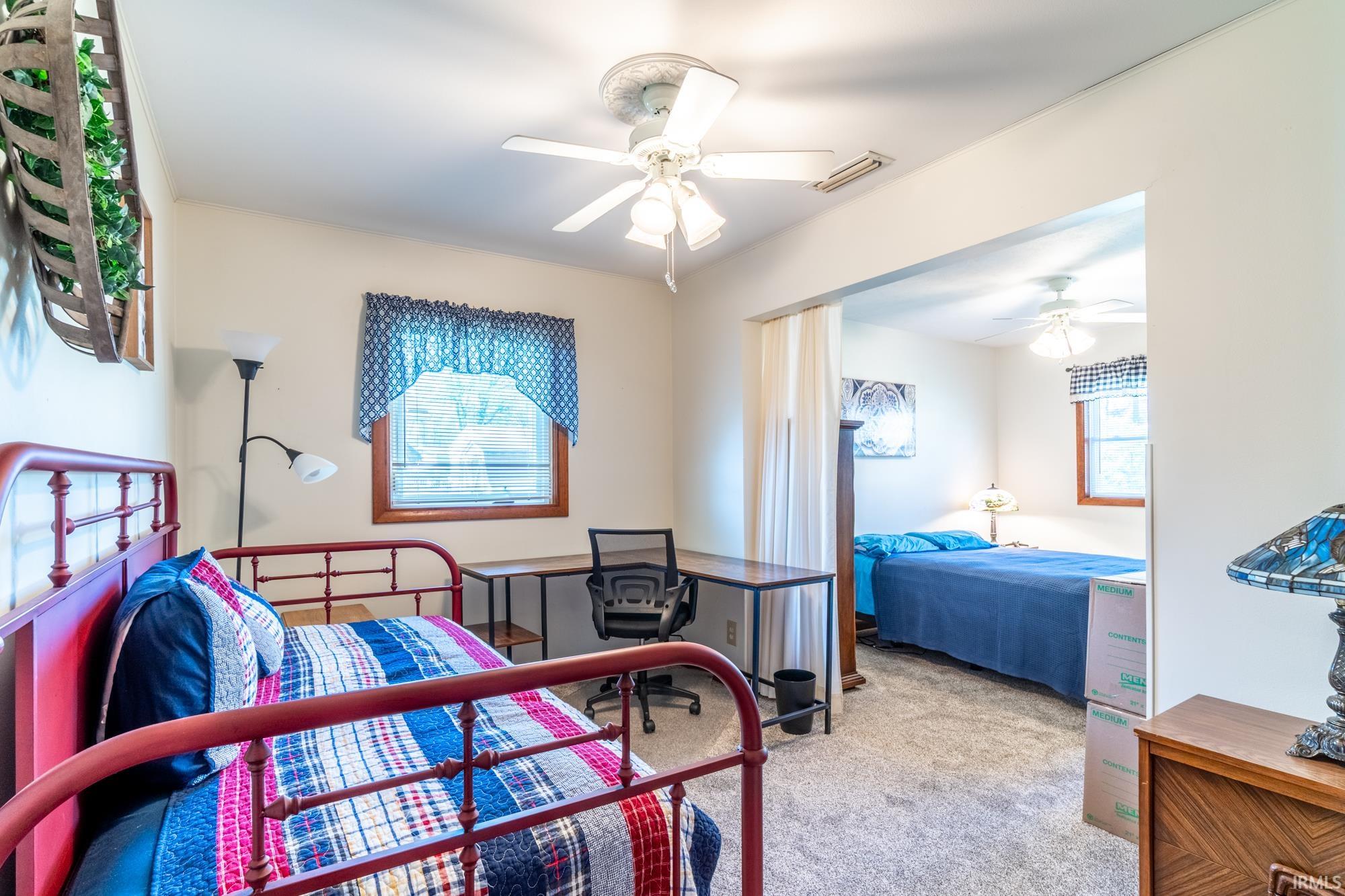 Carpeted room with a ceiling fan, a window with wood trim, and a built-in desk