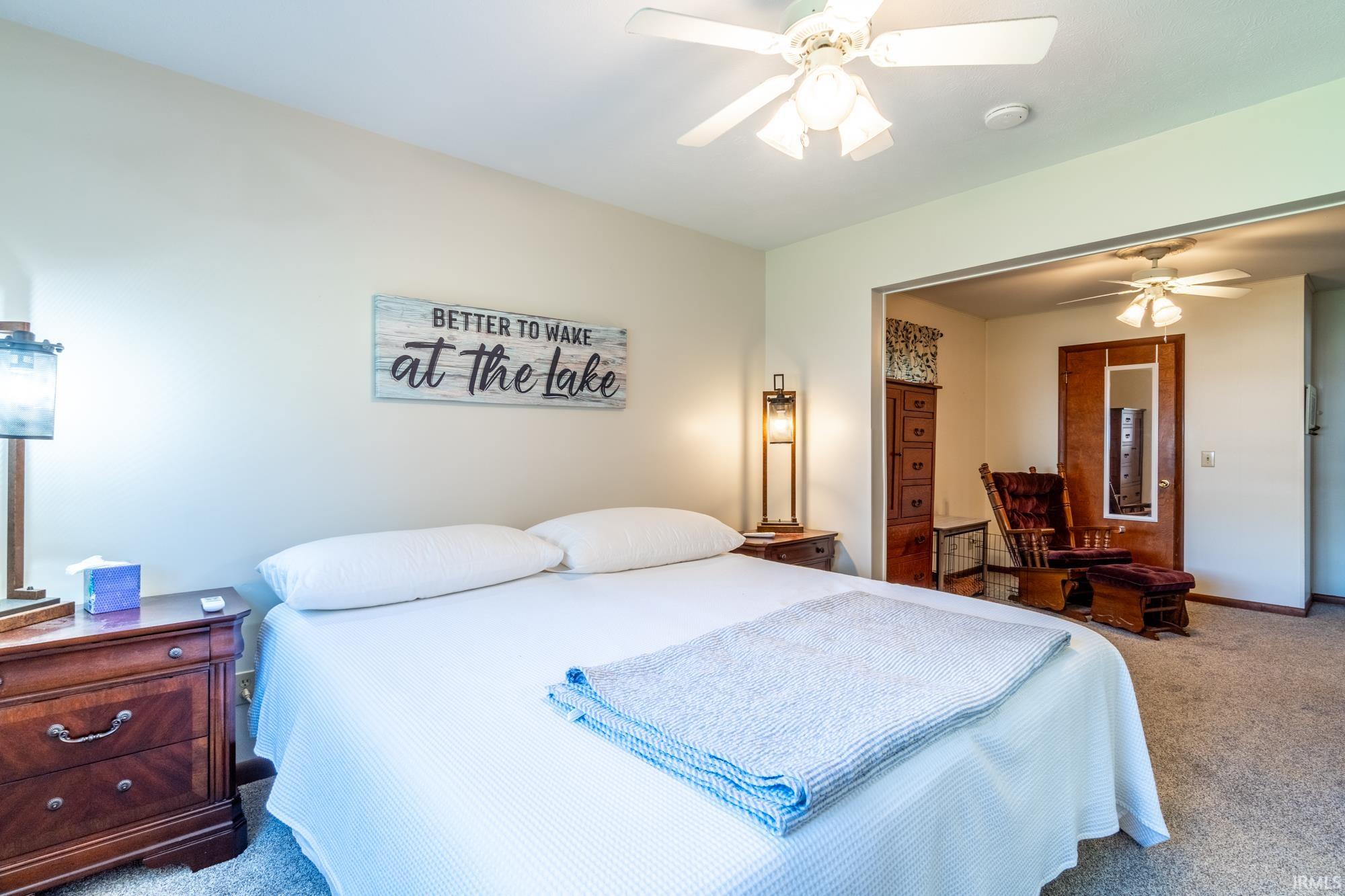 Carpeted bedroom with a ceiling fan light fixture and neutral wall paint