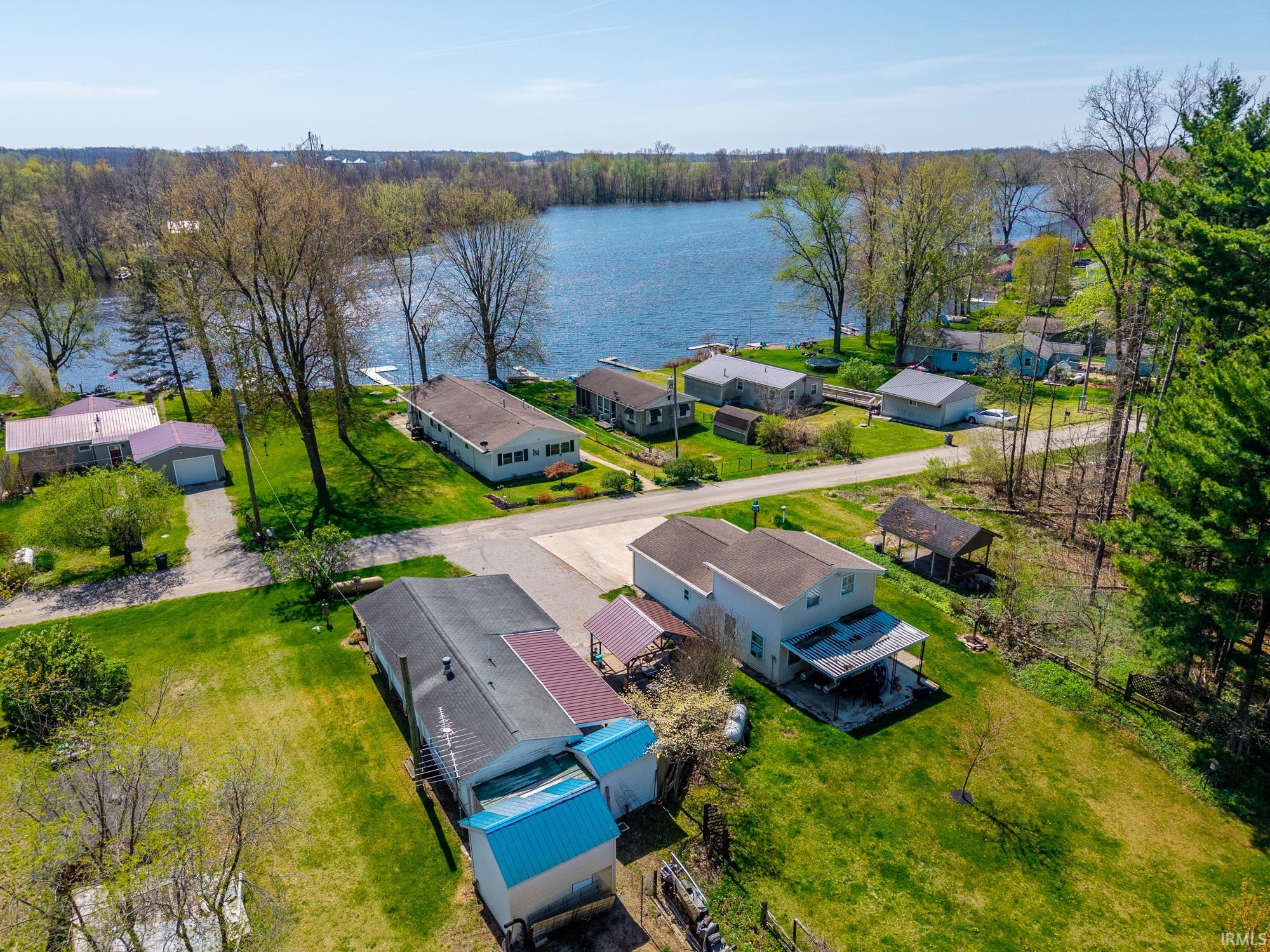 Aerial perspective showcasing a vibrant blue lake with multiple docks, surrounded by established trees and residential properties