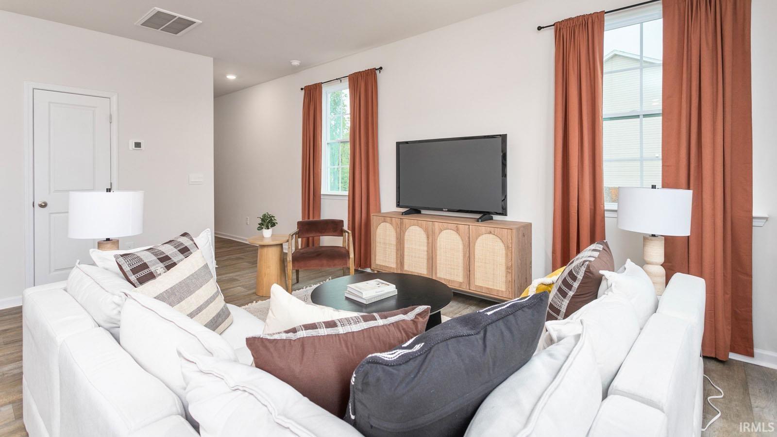 Open-concept living space featuring wood-finish flooring, recessed lighting, and bright white walls