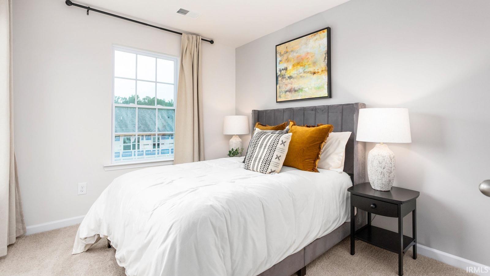 Bedroom featuring light gray walls, carpeted flooring, a white-framed window with grid panes, and a curtain rod