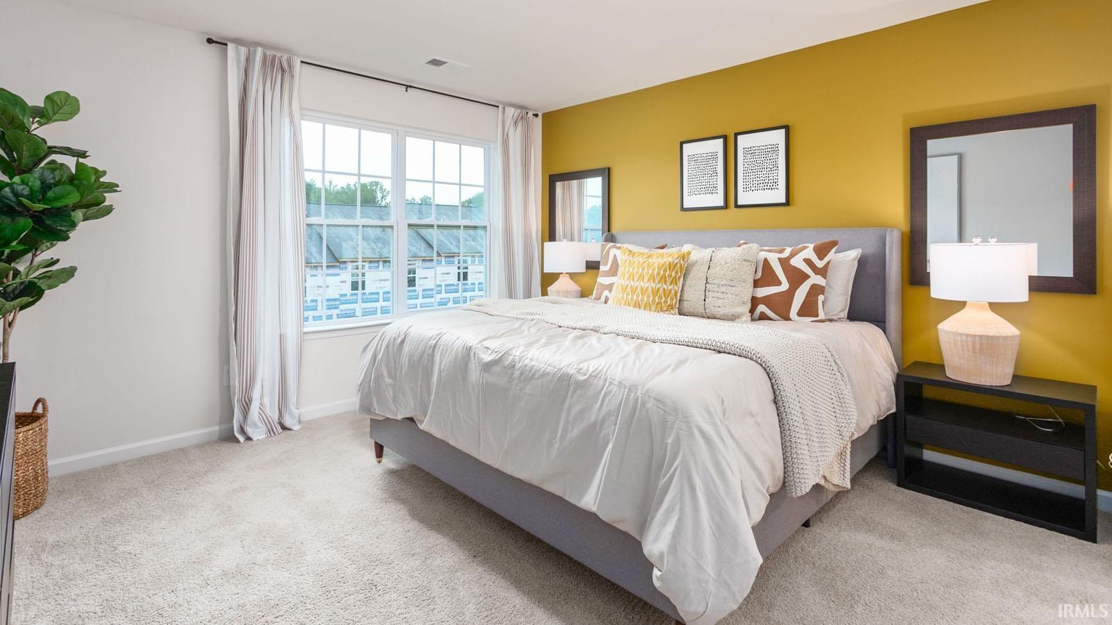 Spacious bedroom featuring light neutral carpeting, a large multipane window, and a feature wall