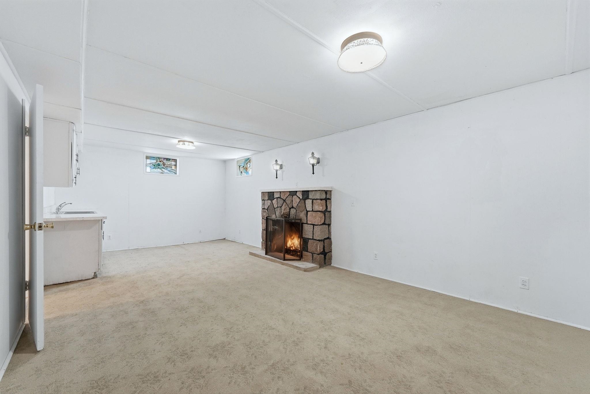 Open concept room featuring a stone fireplace with hearth, built-in cabinetry, and integrated sink