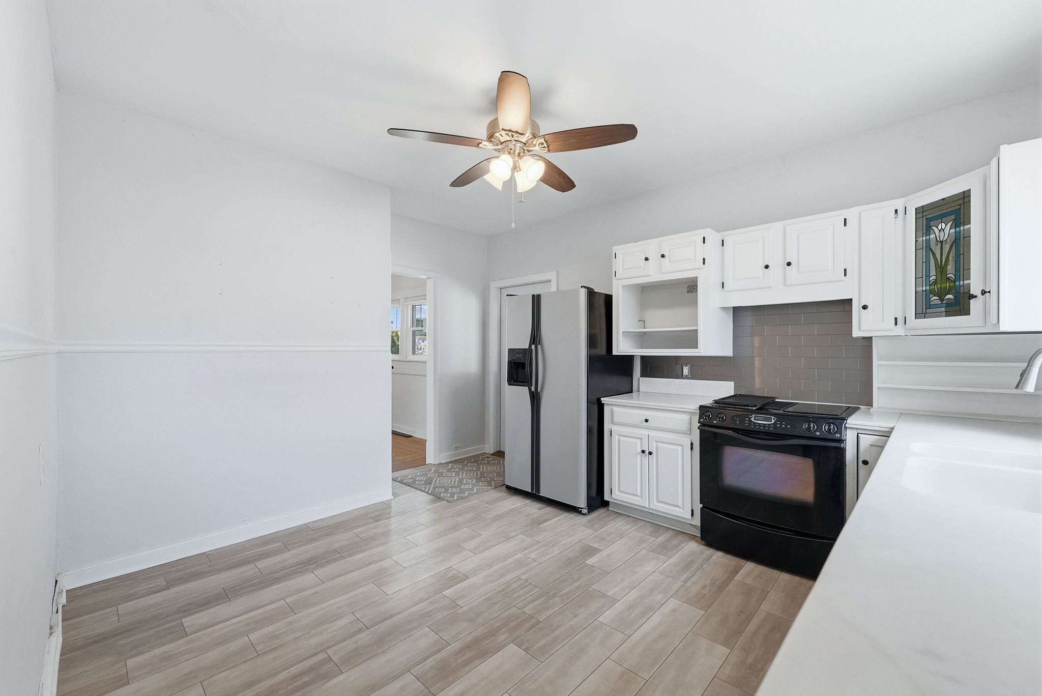 Kitchen featuring white cabinetry, gray subway tile backsplash, and white countertops