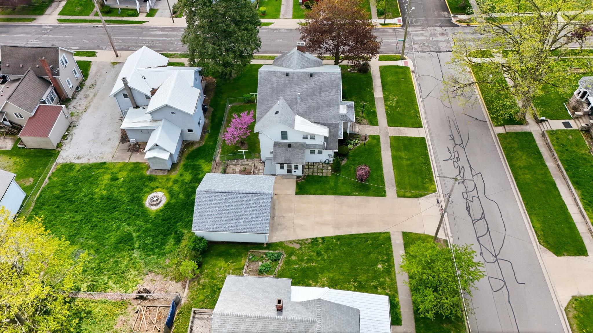 Expansive property featuring a main residence with multiple rooflines, a detached garage, and a large grassy yard with a fire pit