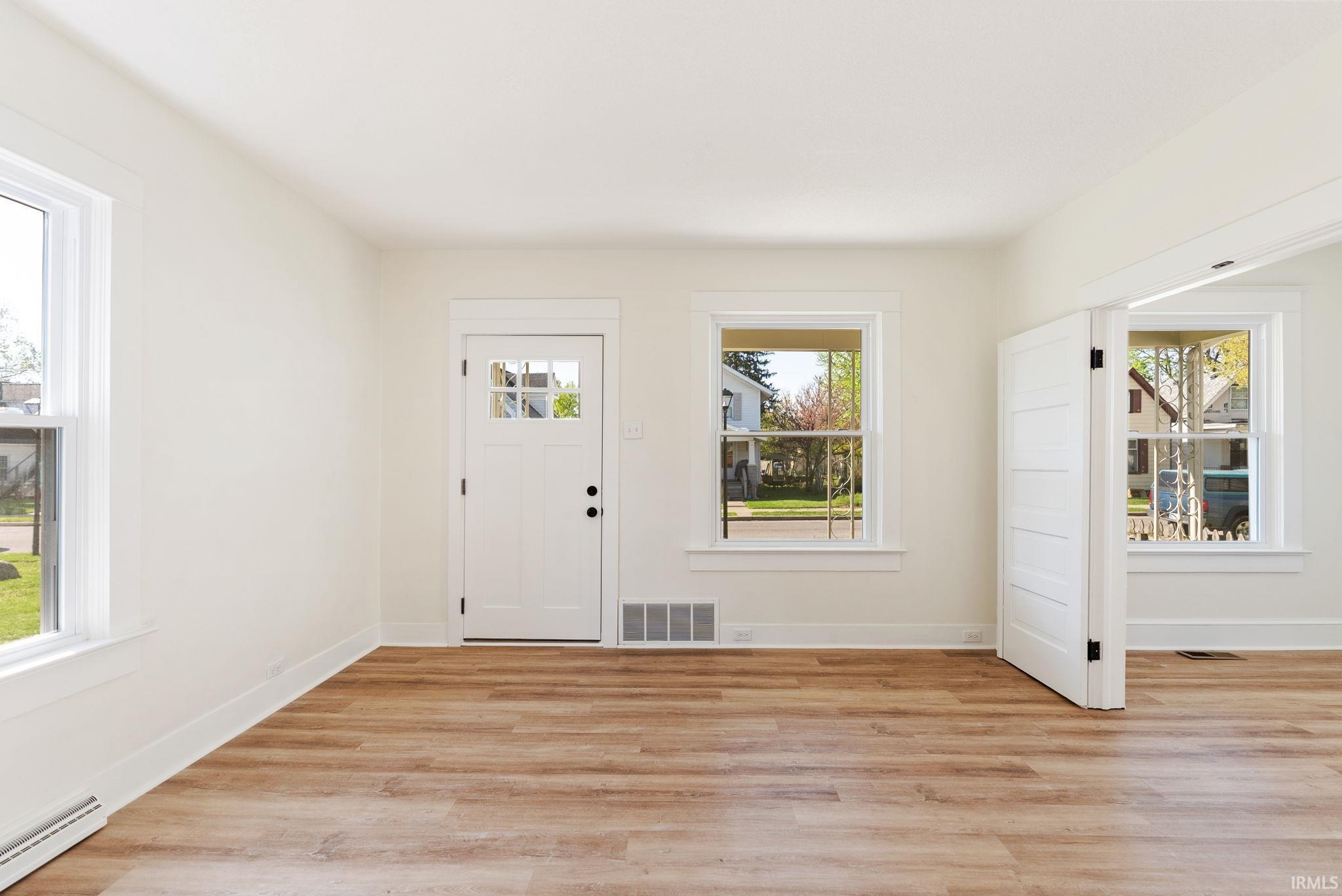 Inviting entry space featuring light wood-finish flooring, crisp white walls, and bright white trim