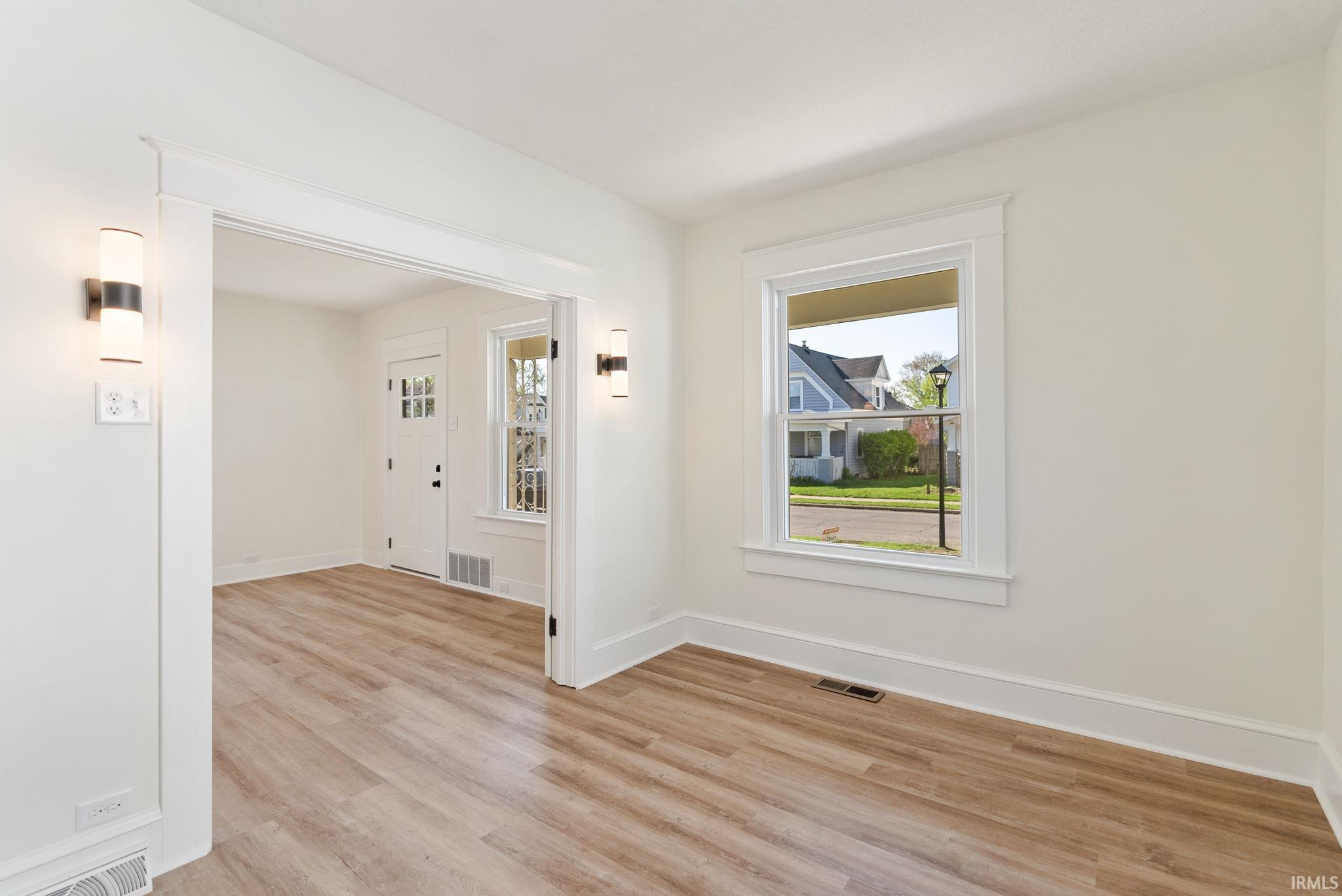 Spacious room with wood-finish flooring and white baseboards