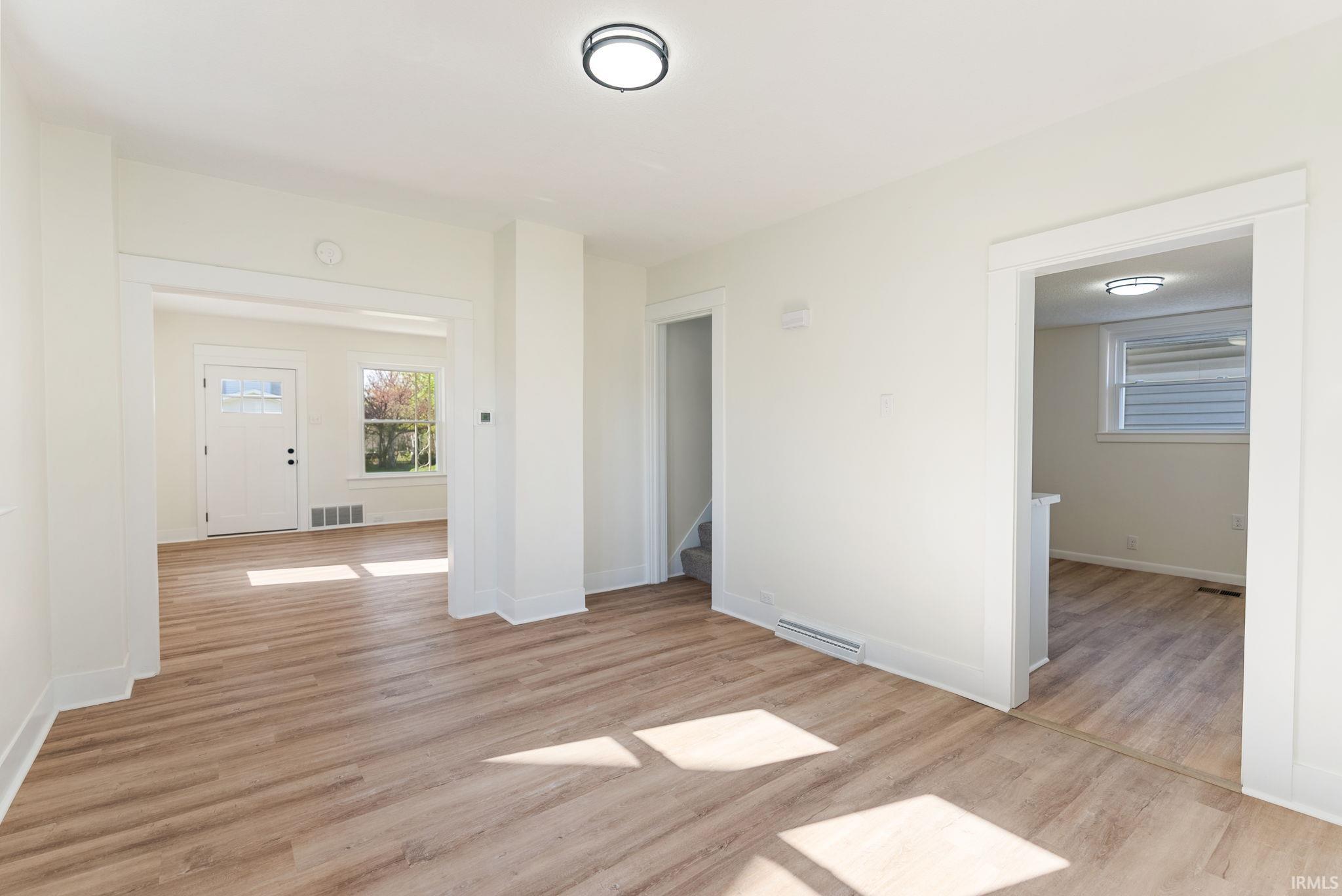 Spacious interior featuring wood-finish flooring, crisp white walls, recessed lighting, and ample natural light through multiple windows