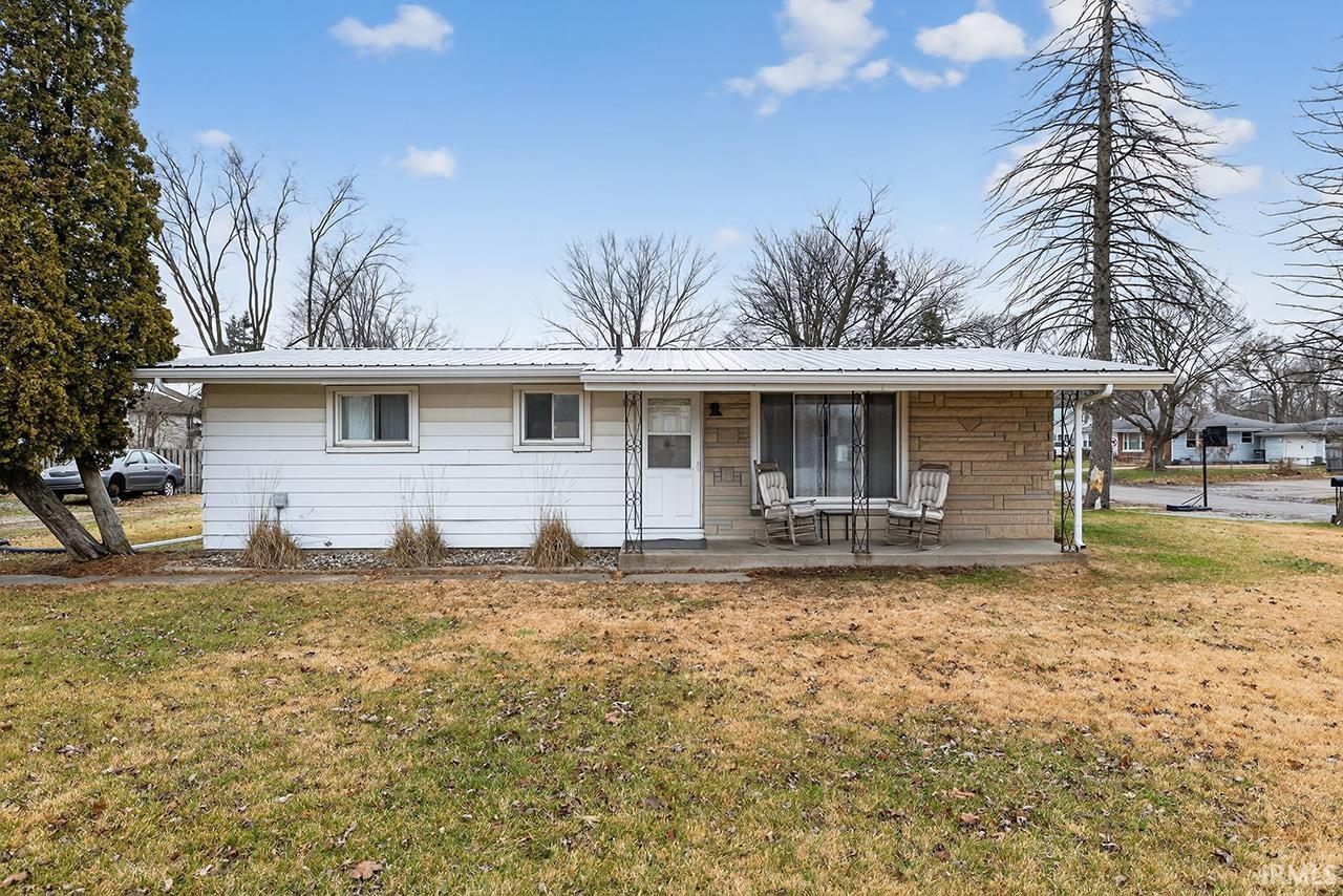 Single story home with a front yard, a porch, and a metal roof