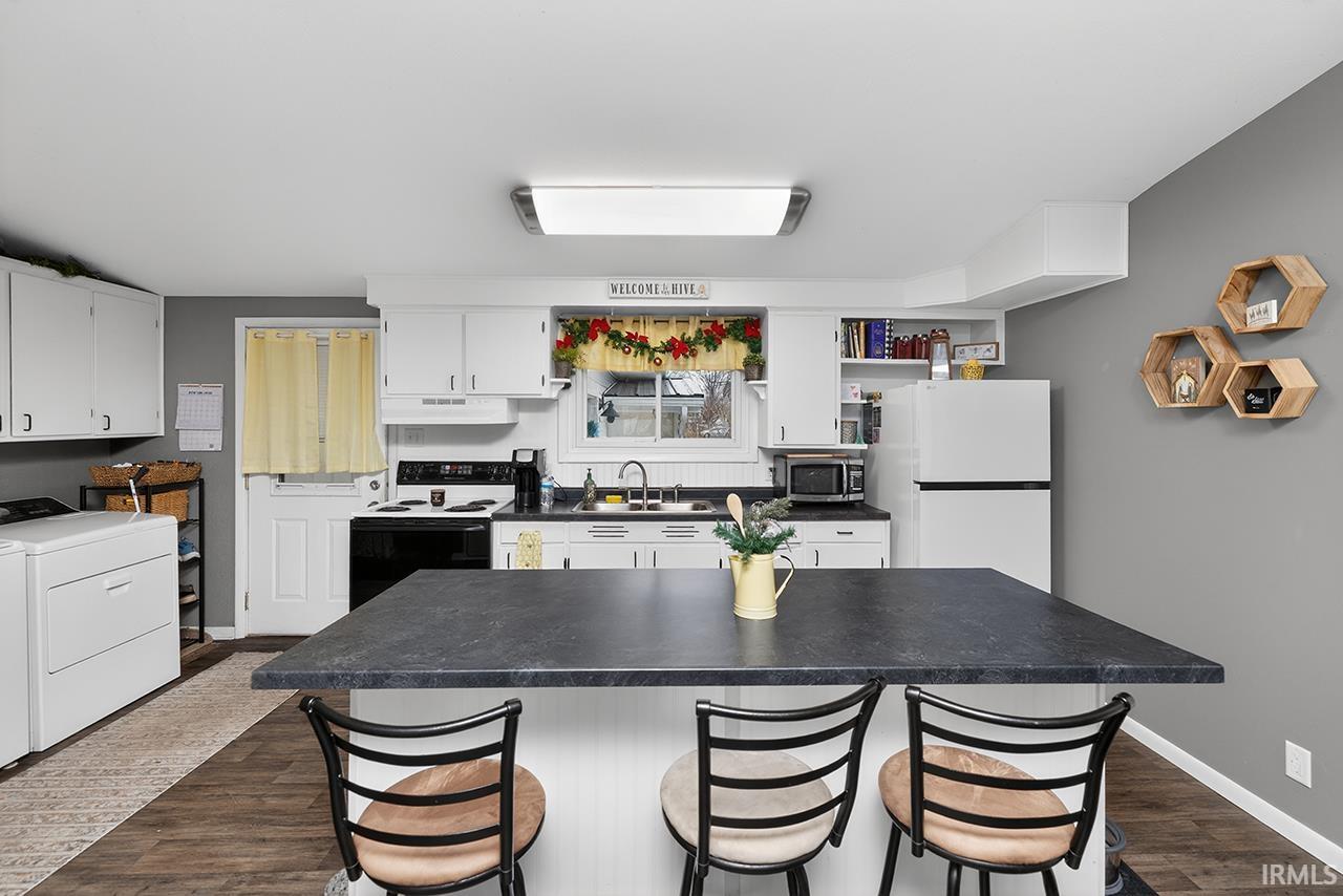 Kitchen featuring white cabinets, washer / dryer, freestanding refrigerator, electric range, and a kitchen island