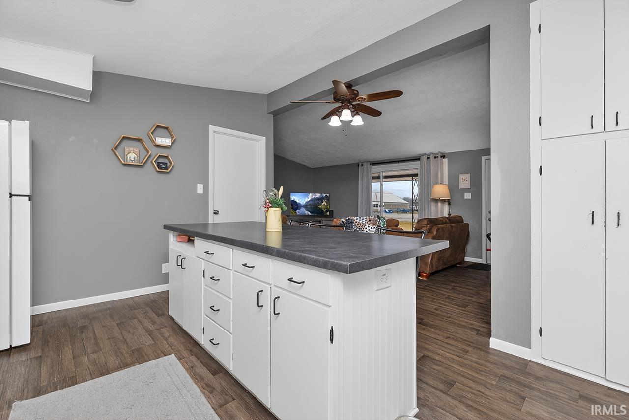 Kitchen with white cabinetry, dark countertops, open floor plan, dark wood-style floors, and freestanding refrigerator