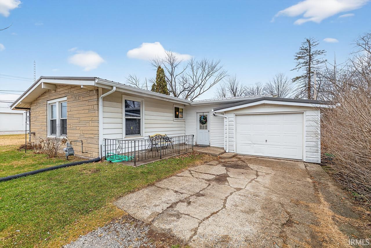 Ranch-style home featuring driveway, an attached garage, a front yard, and stone siding