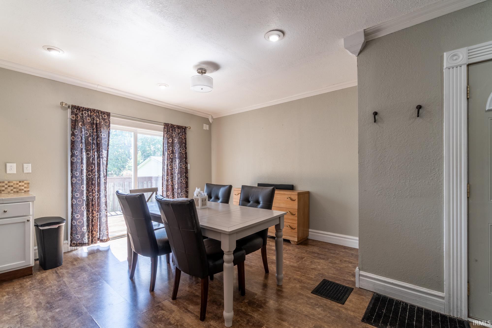 Dining area featuring wood-finish flooring and crown molding