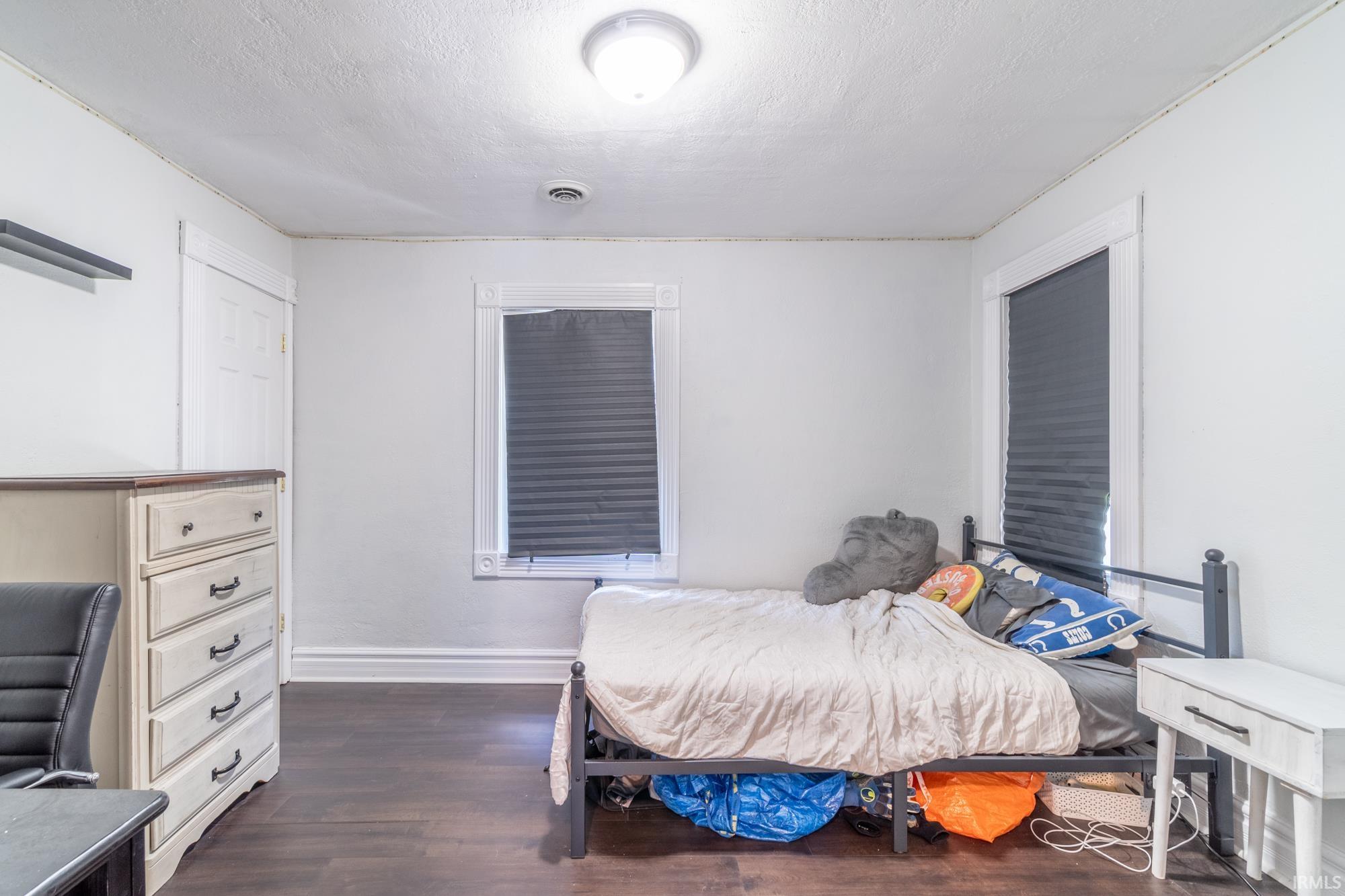 Room featuring wood-finish flooring, white walls, and a ceiling-mounted light fixture
