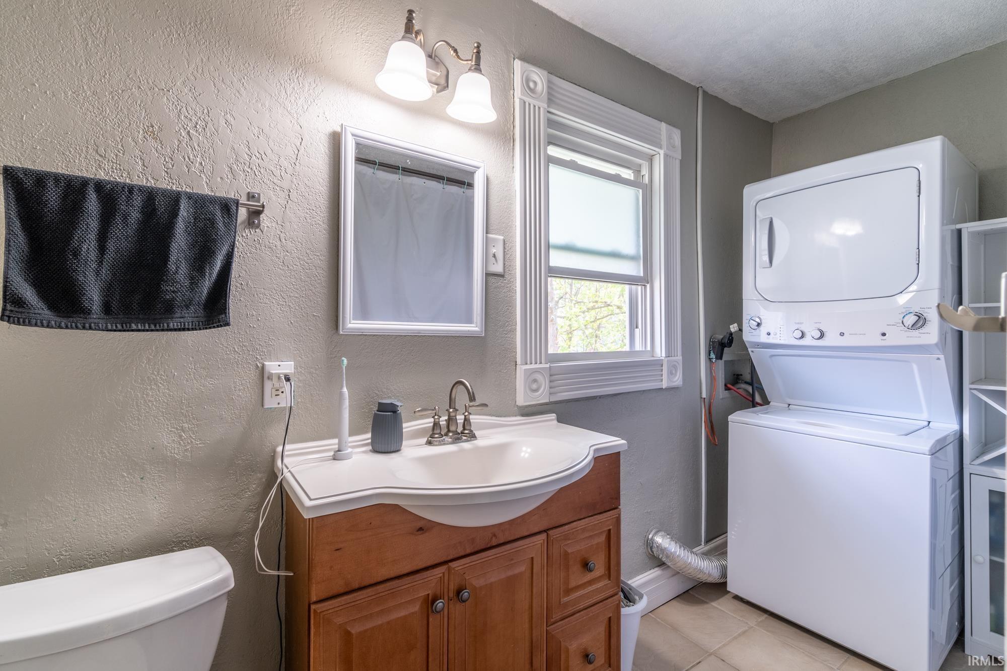 Bathroom featuring a wood-finish vanity with an integrated sink, a wall-mounted mirror, and overhead vanity lighting