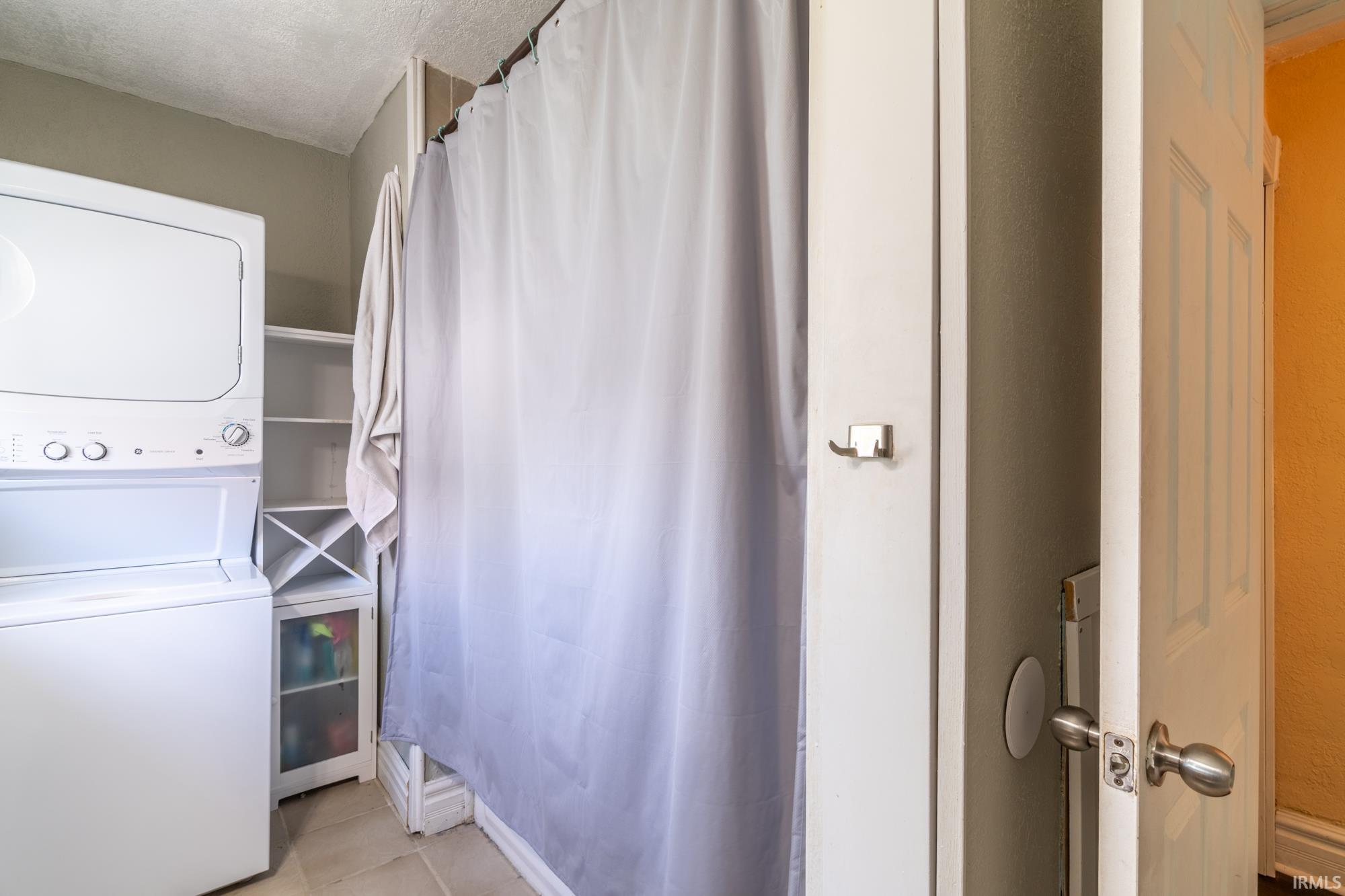 Compact laundry area featuring a stacked washer and dryer unit