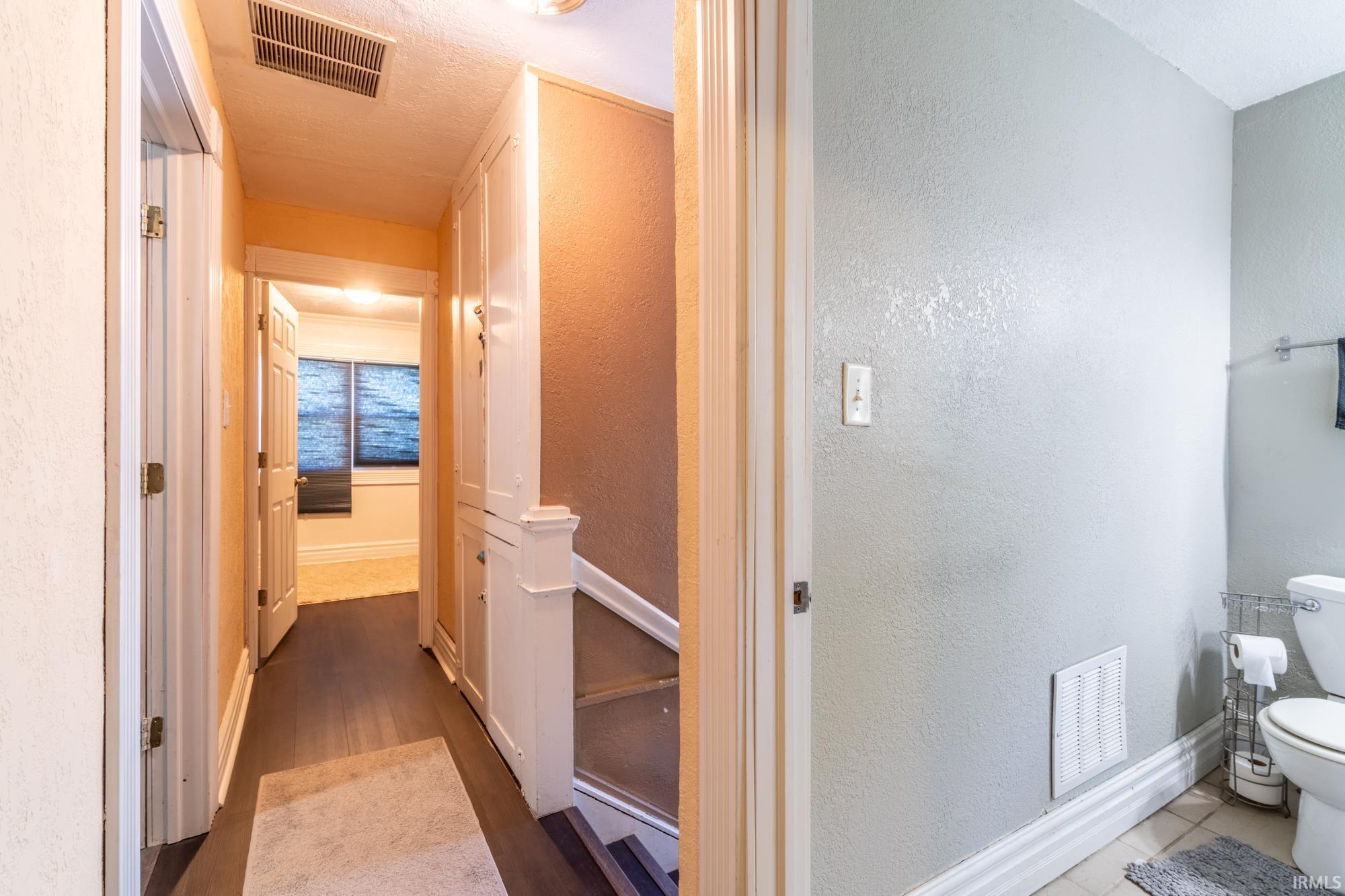 Hallway featuring dark wood-finish flooring, built-in cabinetry, and white baseboards