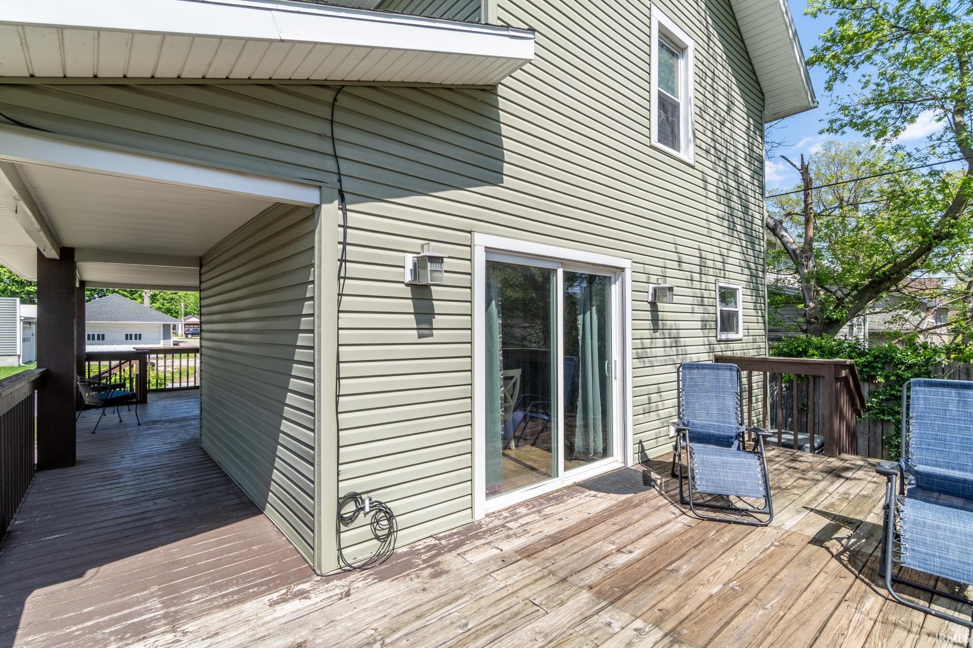 Expansive wood deck with a covered porch area and a sliding glass door entry to the residence