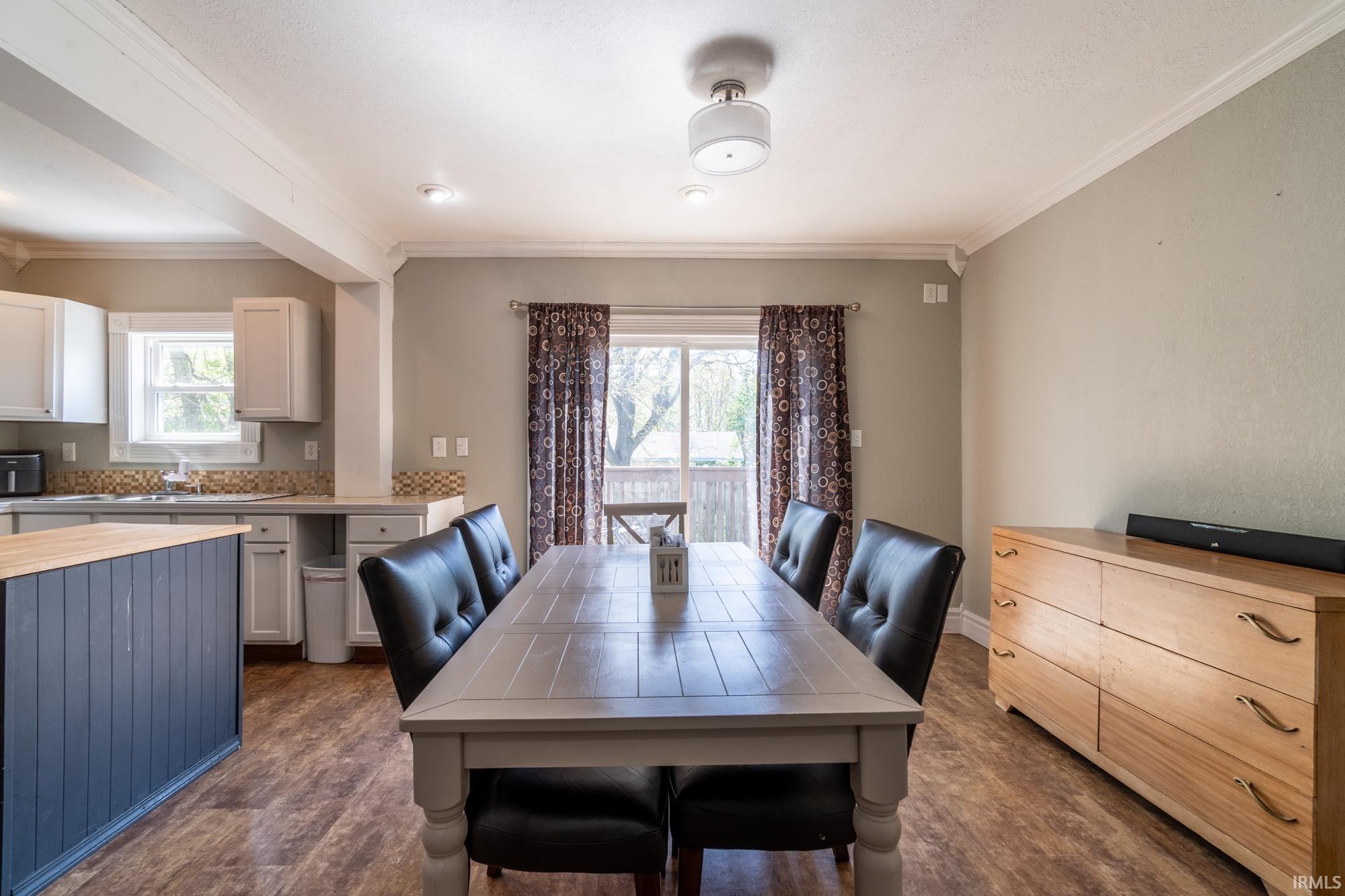 Dining area featuring wood-finish flooring, crown molding, and a sliding glass door